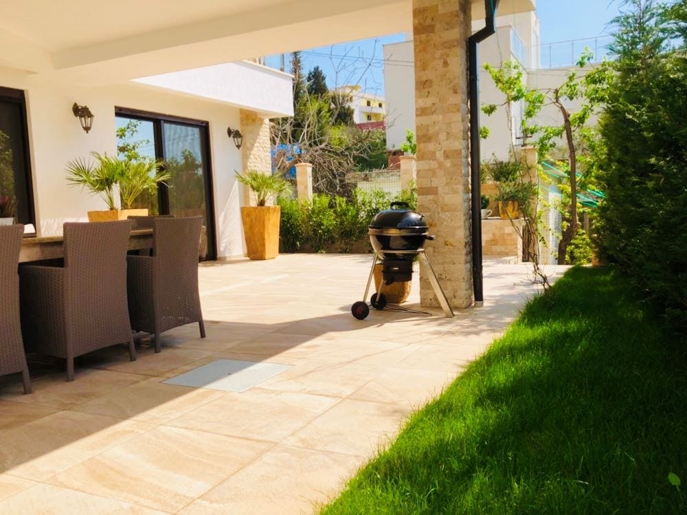 Terrace of a house in Dobri Vody, Montenegro: dining area, grill, stone finishes, and a green garden by the villa.