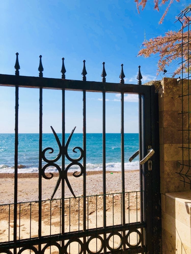Sea and beach view through the wrought-iron gate of a house in Dobra Voda, Montenegro. Direct access to the Adriatic coast.