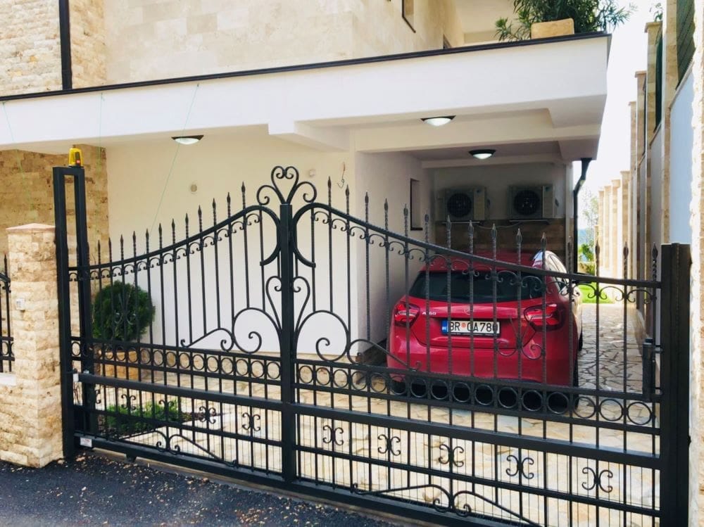 Private house in Dobri Vody, Montenegro: wrought-iron gate, covered parking for a car, and stone facade cladding.