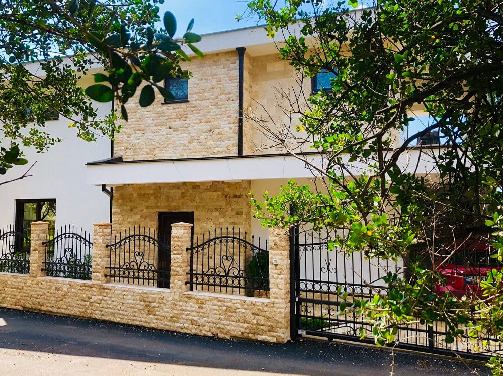 Modern house in Dobri Vody, Montenegro: natural stone facade, wrought-iron fence, and entrance gates.