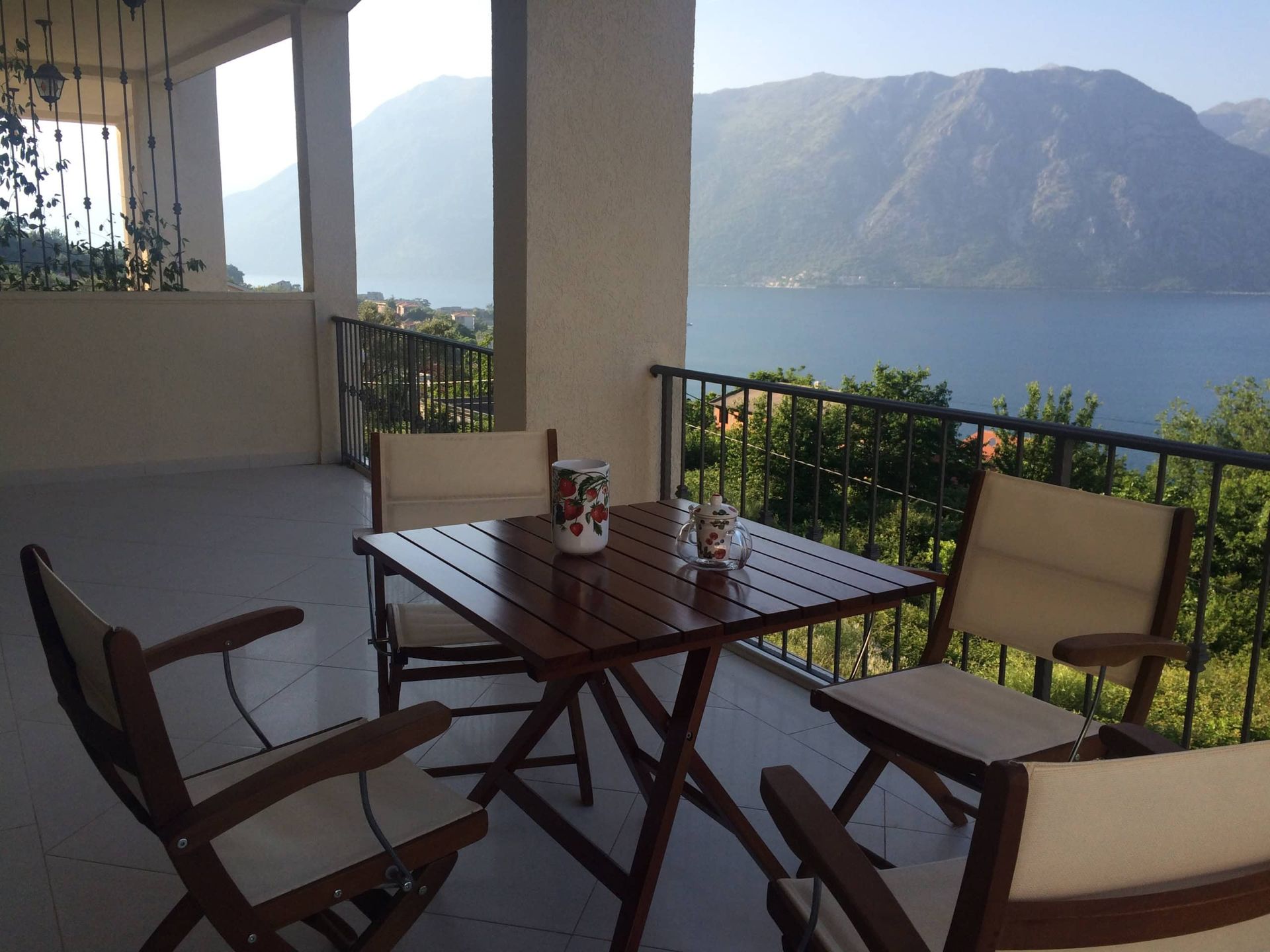 Terrace with wooden furniture and panoramic views of Kotor Bay and the mountains, apartment in Prčanj, Montenegro.