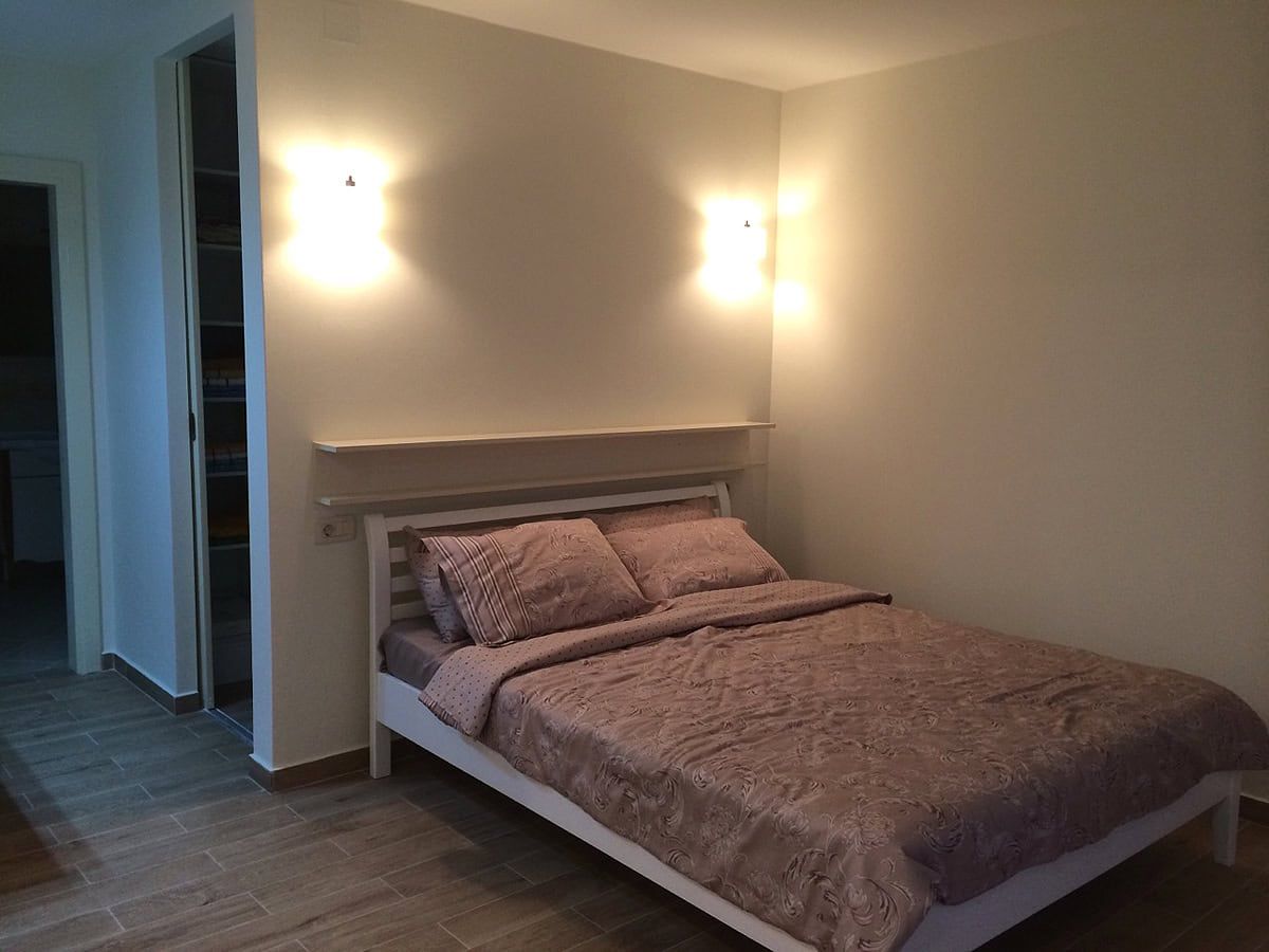 Cozy bedroom with a double bed in an apartment, Prčanj, Montenegro: bright interior, wall lights.