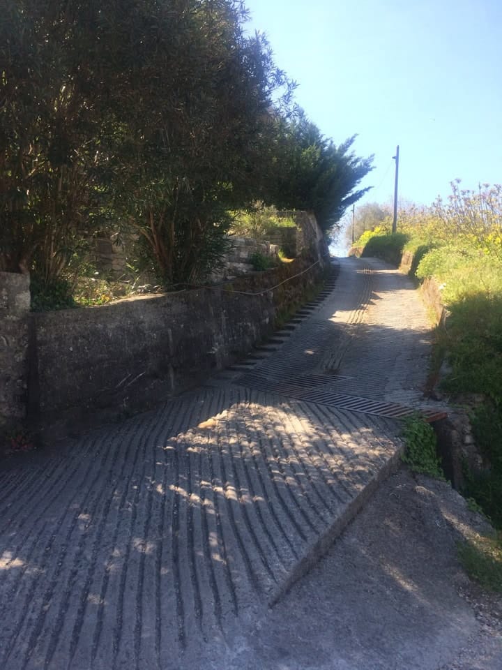 Concrete road with textured paving and a stone retaining wall by a house in Prčanj, Montenegro.
