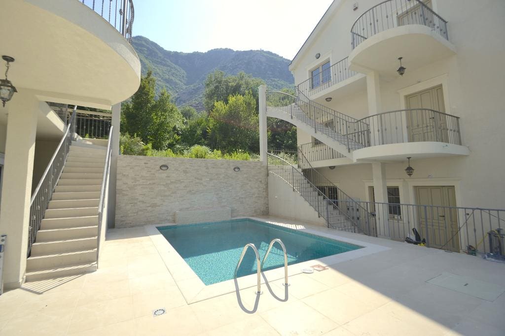 Pool by a villa in Prčanj, Montenegro: open terrace, stone finish, and mountain views by the residential complex.