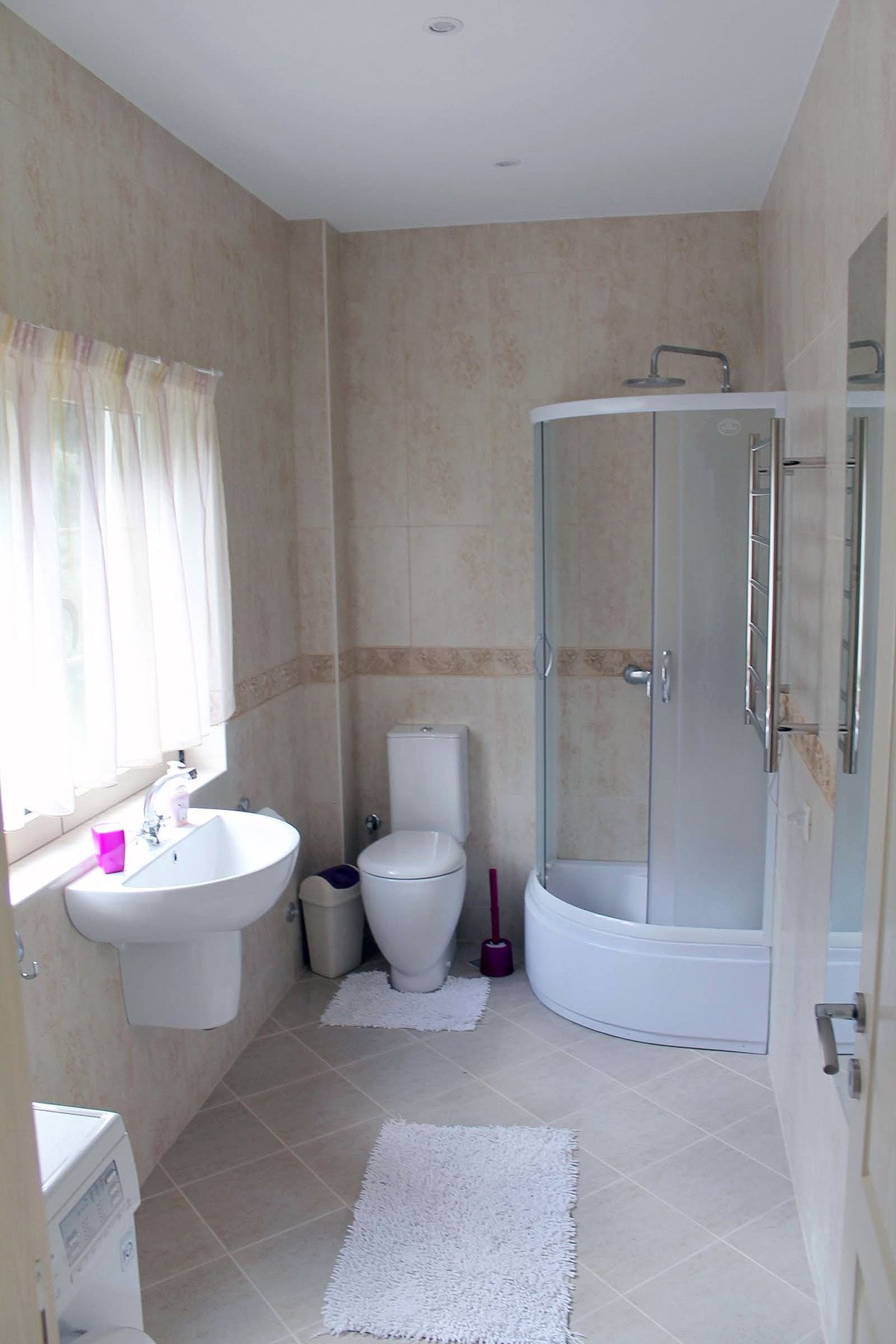 Bright bathroom with a shower cabin in an apartment, Prčanj, Montenegro: tiles, fixtures, and a window with curtains.