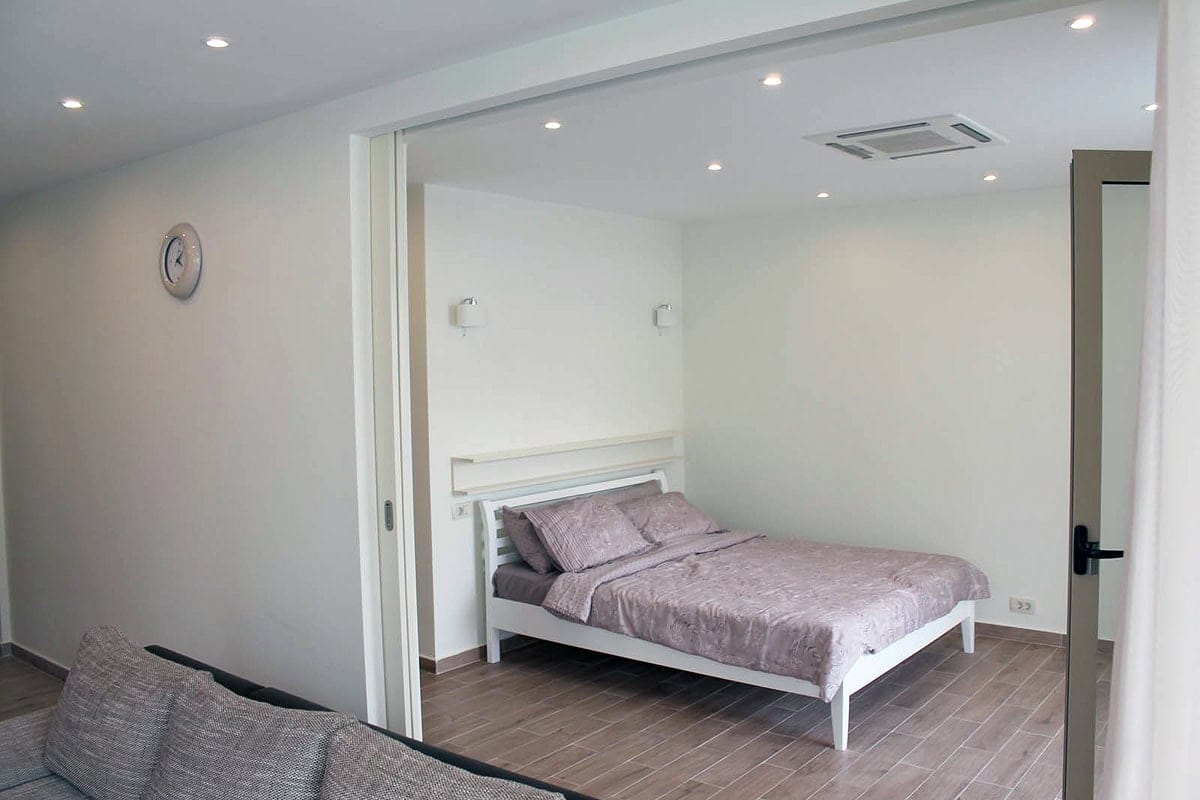 Modern bedroom with a double bed in an apartment in Prčanj, Montenegro, with light finishes and recessed lighting.