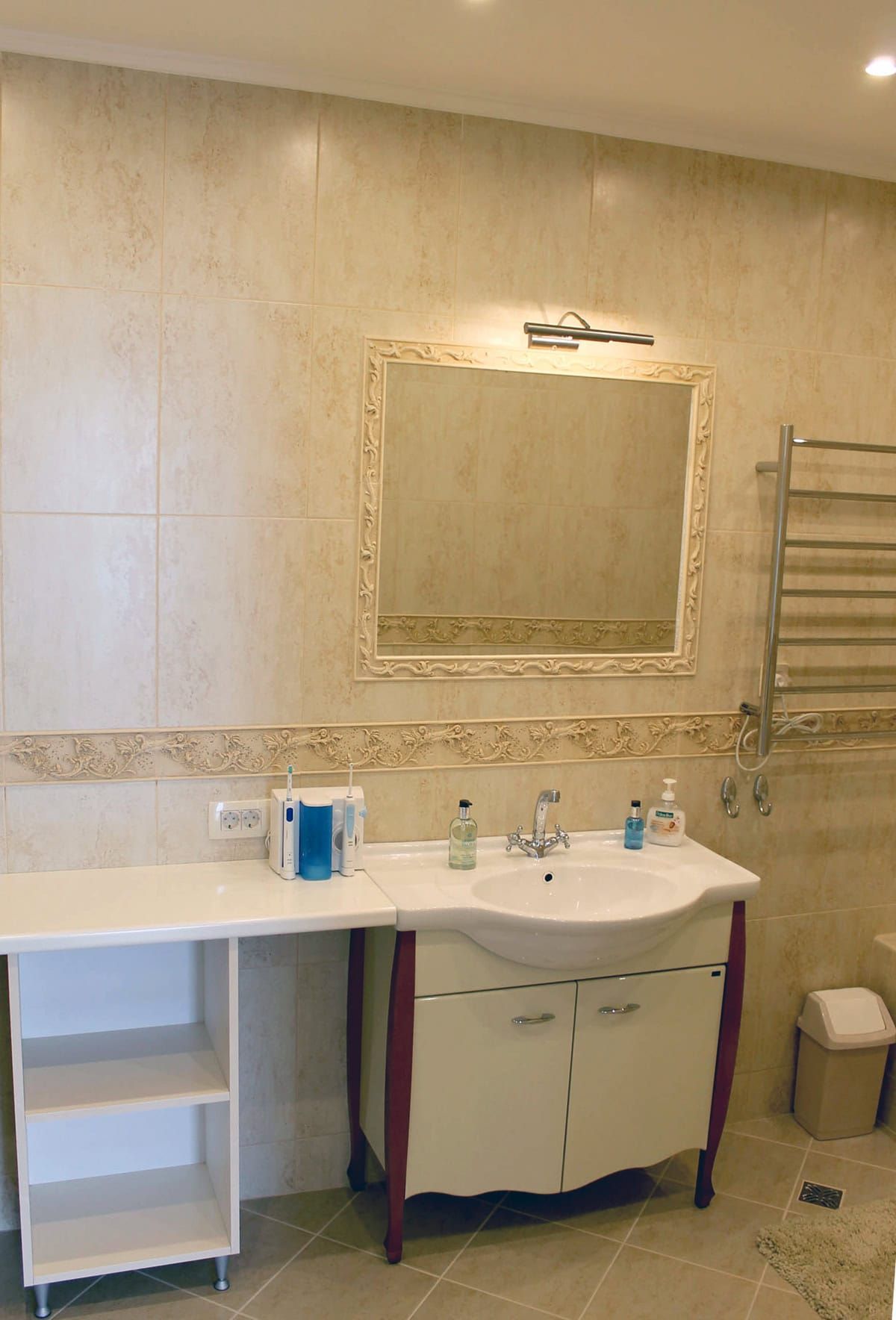 Bright bathroom in an apartment, Prčanj, Montenegro: beige tiles, vanity with sink, mirror, and towel warmer.