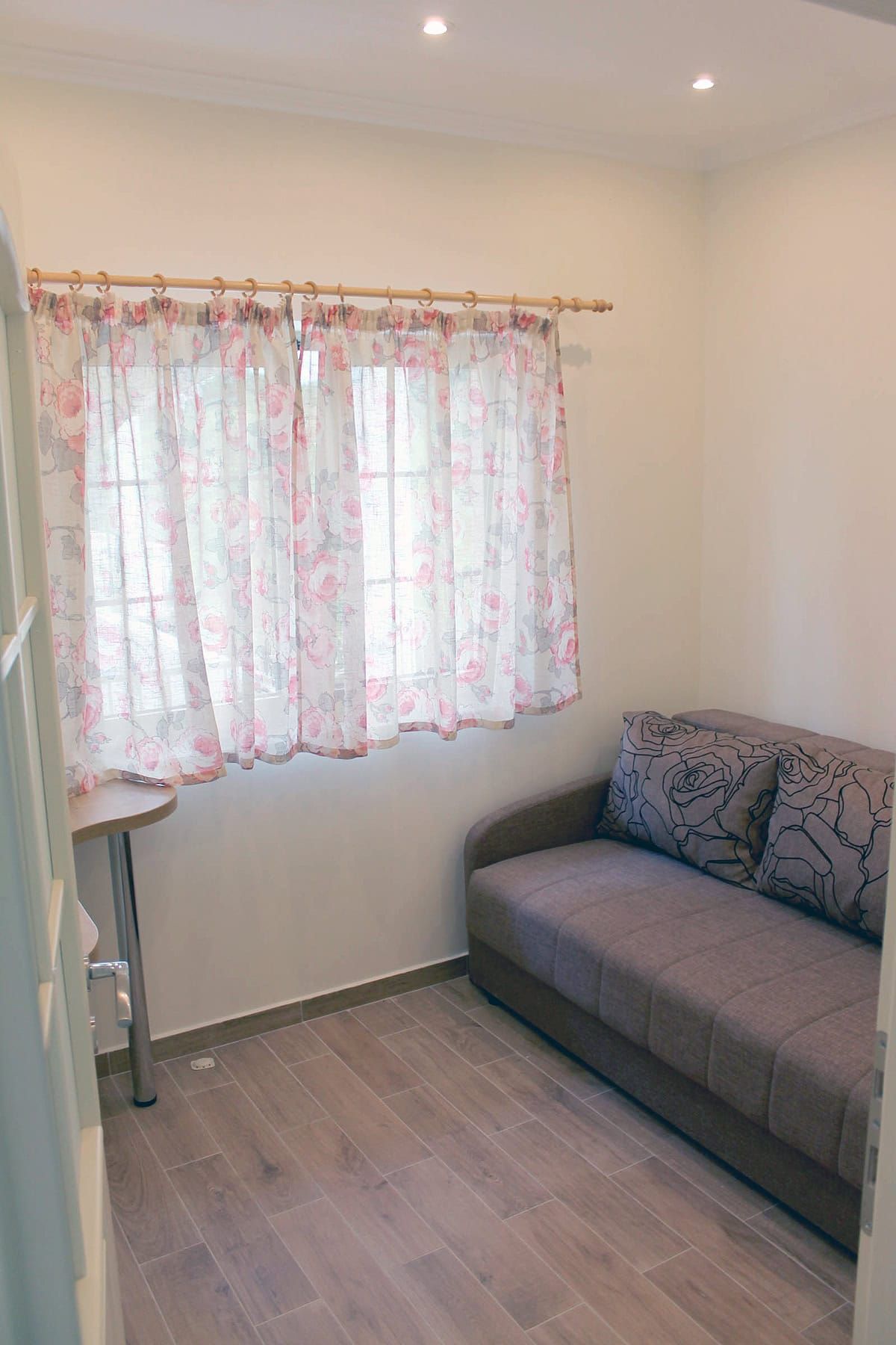 Cozy living room with a sofa and floral print curtains in an apartment for sale, Prčanj, Montenegro.