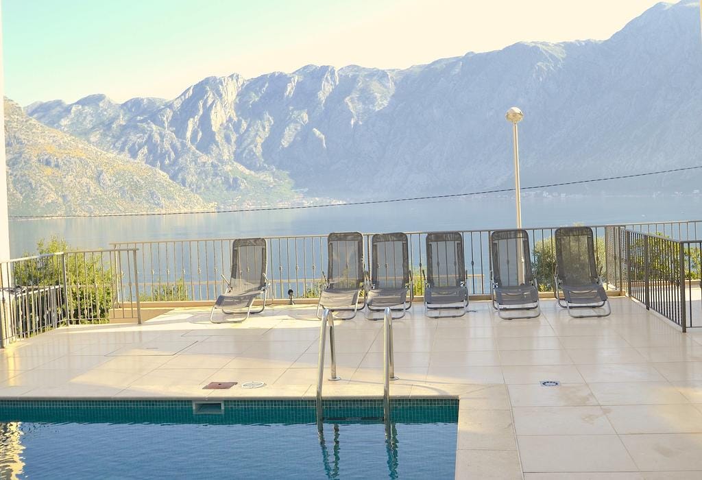 Pool with sun loungers and panoramic views of Kotor Bay and the mountains, Prčanj, Montenegro.