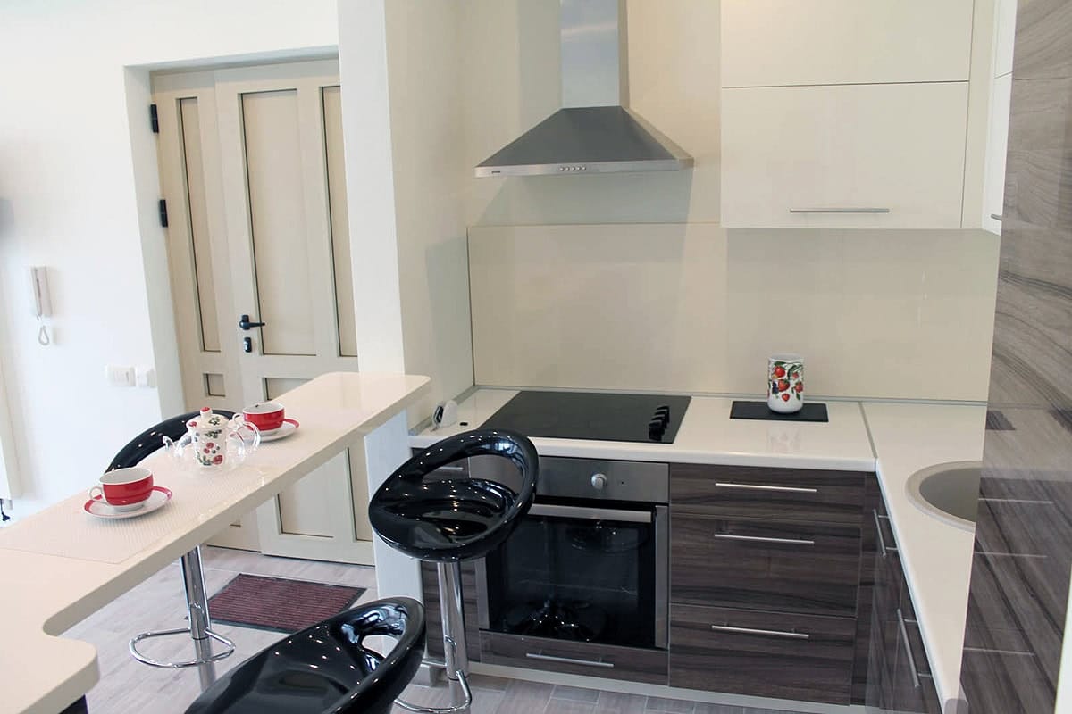Modern kitchen with a breakfast bar and black stools in an apartment for sale in Prčanj, Montenegro.