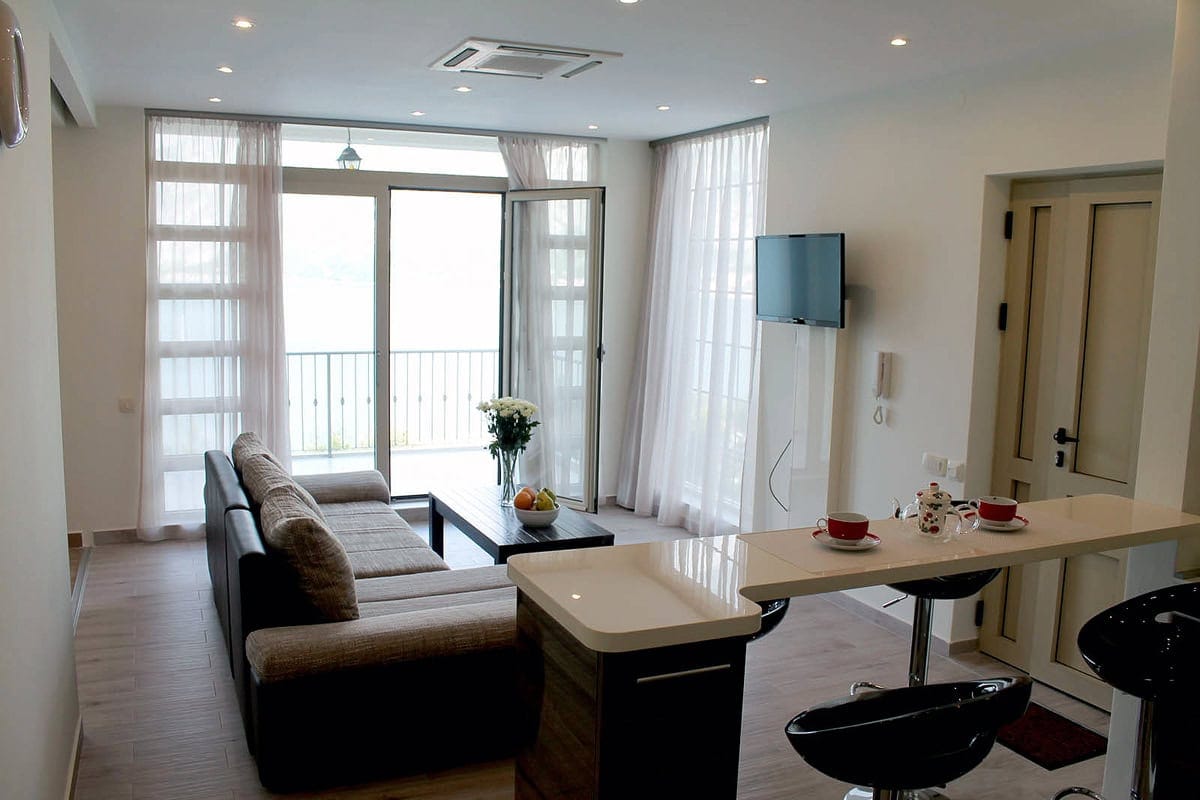 Living room with a sofa and breakfast bar in an apartment in Prčanj, Montenegro, with access to the balcony and sea view.
