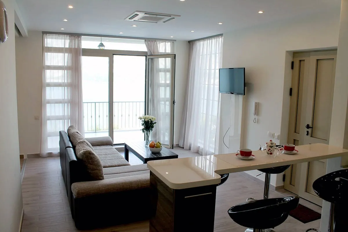 Living room featuring a sofa, coffee table, bar counter with stools, and TV near balcony doors.