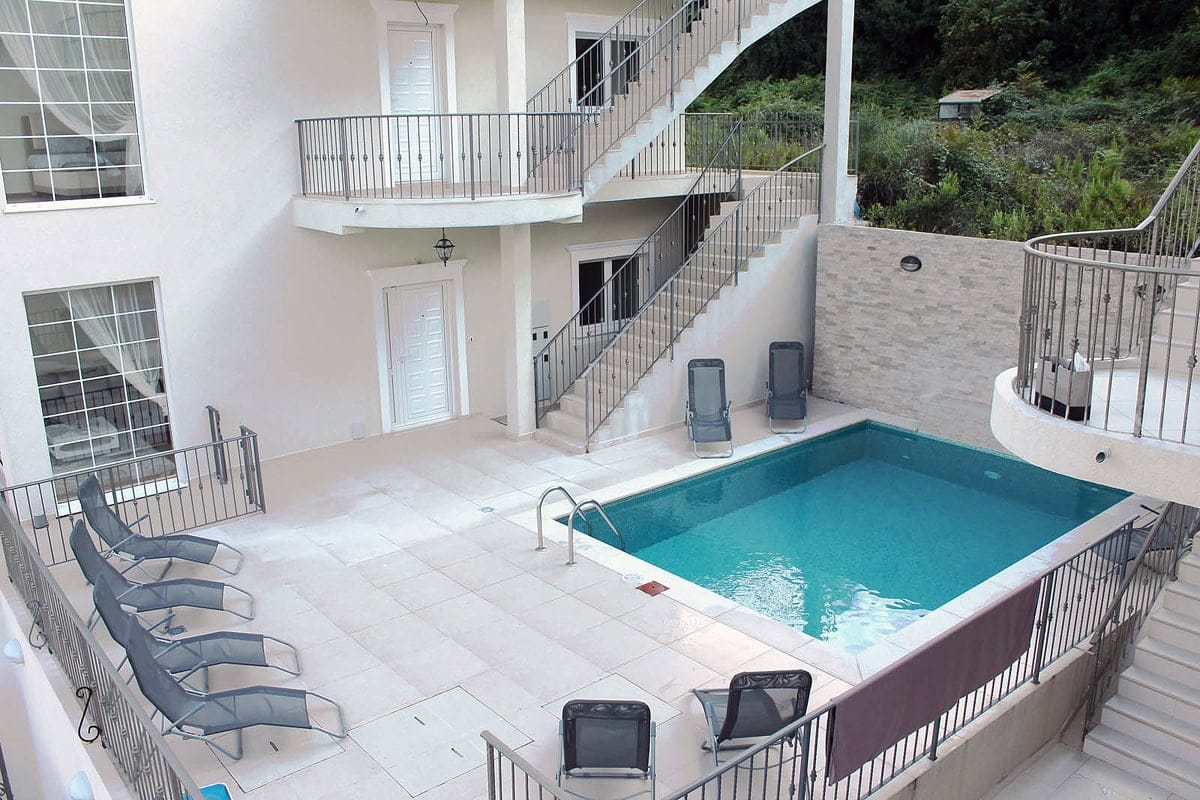 Pool at a villa in Prčanj, Montenegro: a relaxation area with sun loungers, a stone-finished terrace, and an exterior staircase.