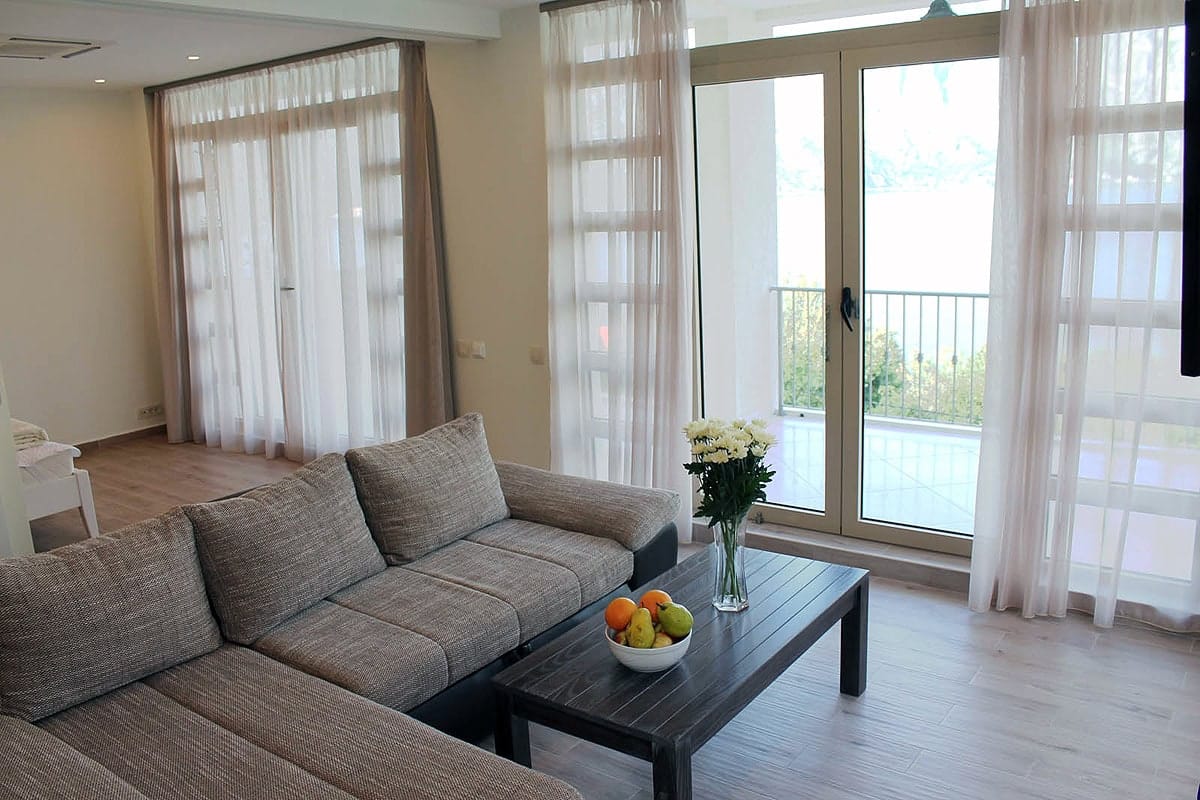 Living room in an apartment in Prčanj, Montenegro: gray sofa, dark coffee table, and access to a balcony with sea view.