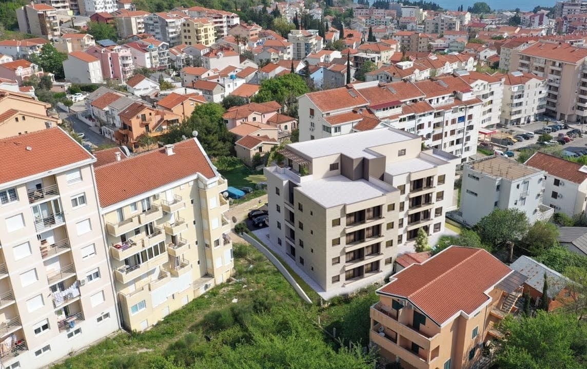 Aerial view of a modern residential complex in Budva, Montenegro, among urban buildings with tiled roofs.