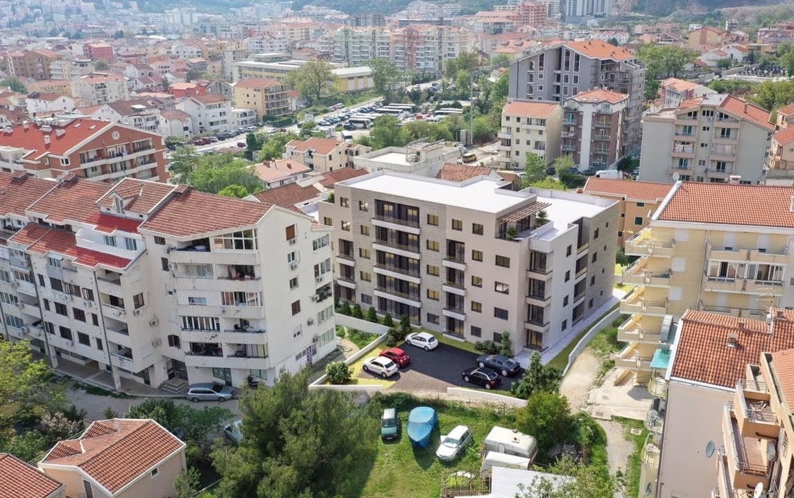 Aerial view of a modern residential complex in Budva, Montenegro, with private parking and urban development.