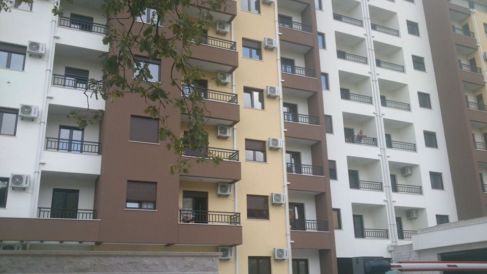 Facade of a modern residential complex in Budva, Montenegro: a multi-story building with balconies and external air conditioning units.