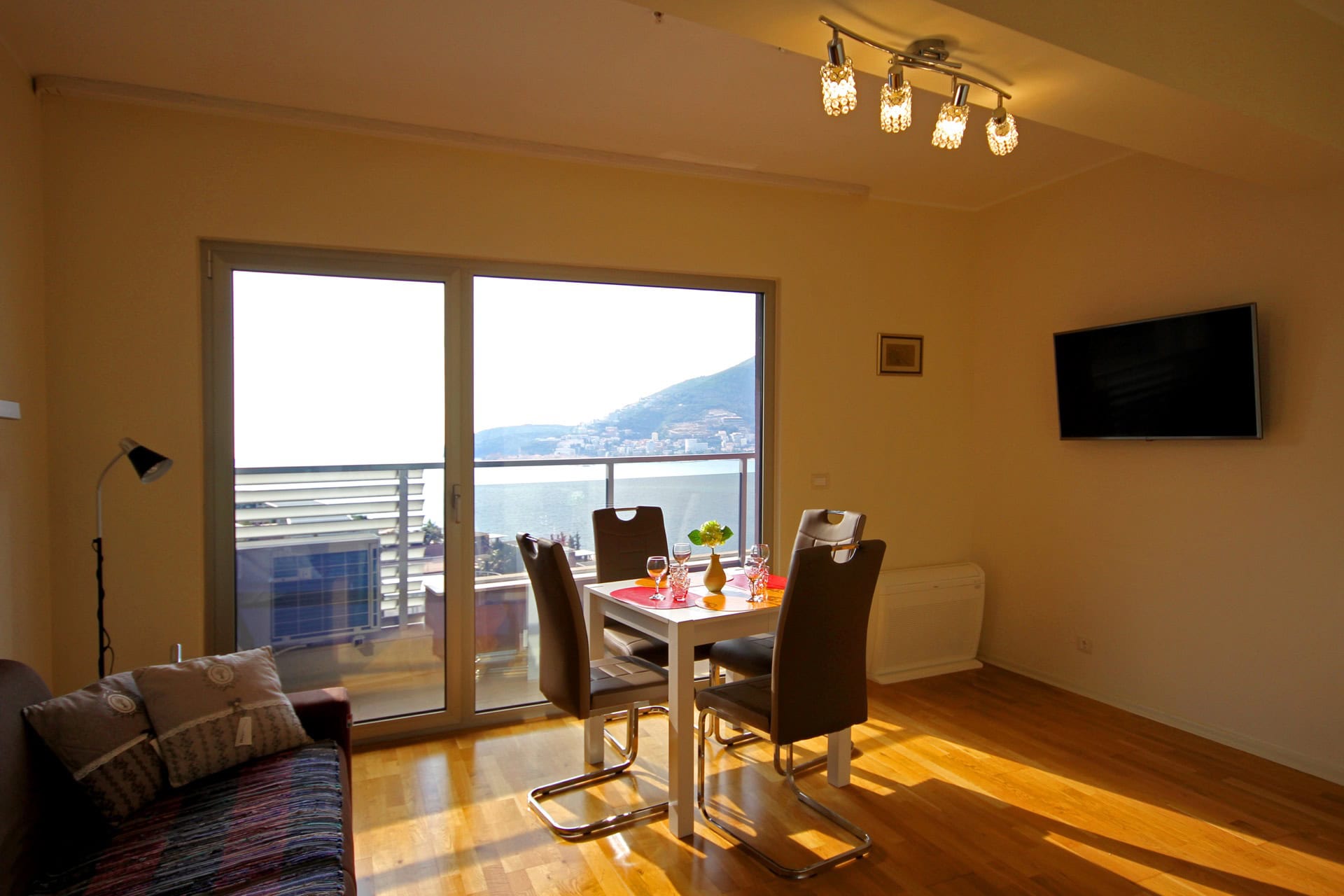 Living room with dining area and panoramic sea view in an apartment in Bečići, Montenegro: modern furniture and parquet flooring.