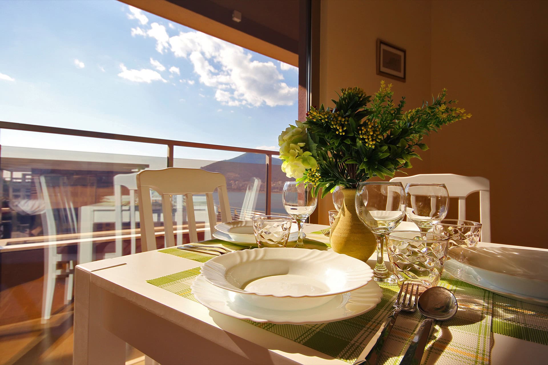 Table setting in the apartment living room in Bečići, Montenegro, with a panoramic view of the sea and mountains through the balcony.