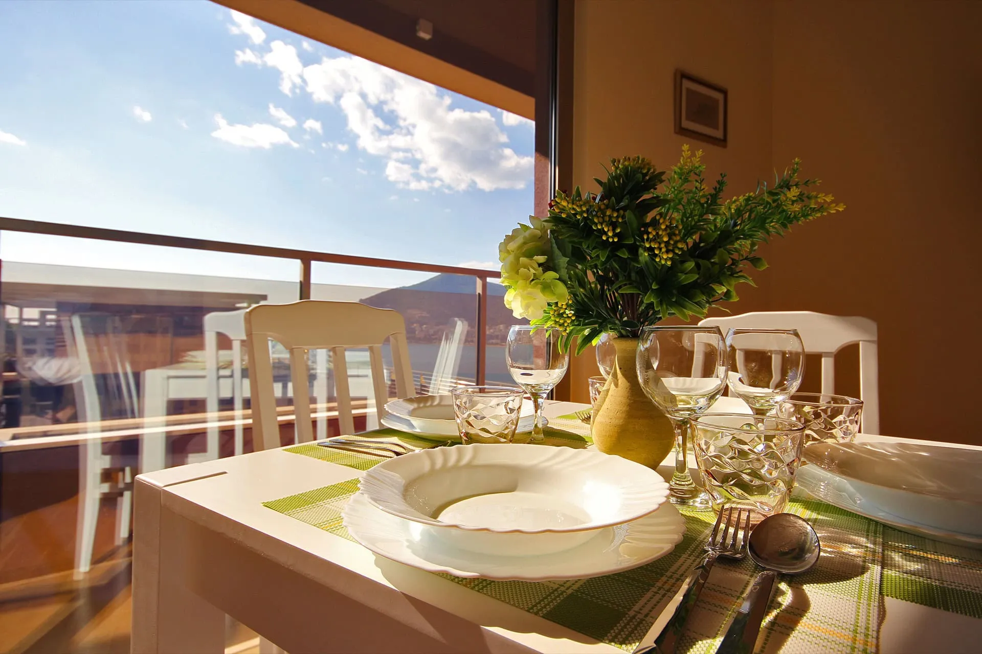 Set dining table near a large window overlooking a balcony and water view.