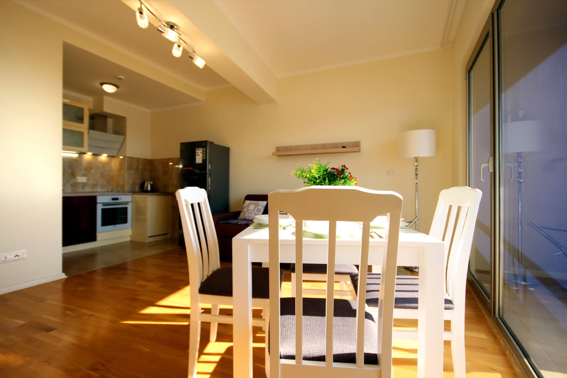 Living room with dining area and kitchen in an apartment, Becici, Montenegro: light furniture, parquet flooring, and panoramic glazing.