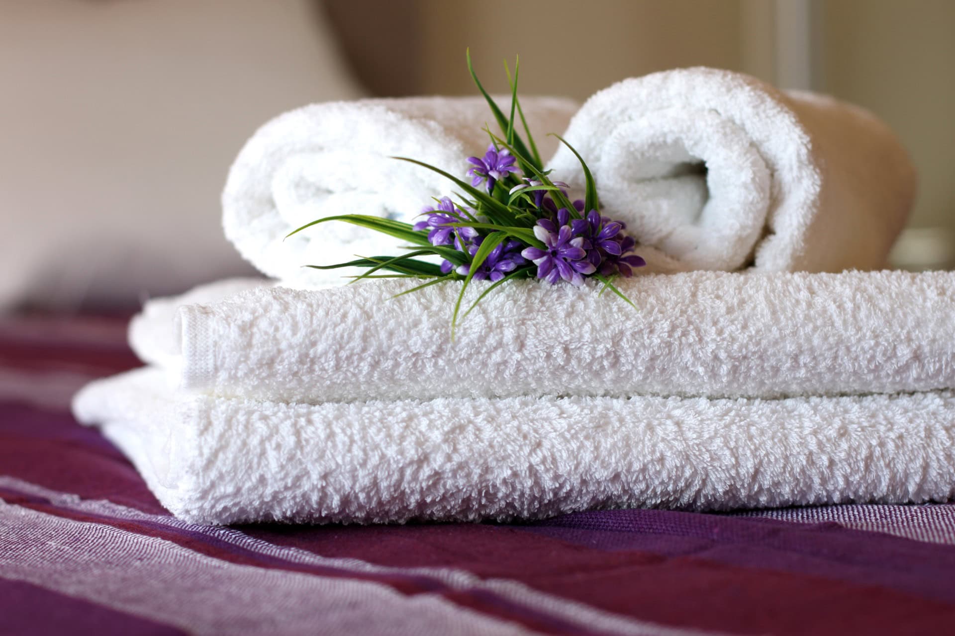 White terry towels with flowers on the bed in the bedroom of an apartment in Becici, Montenegro.