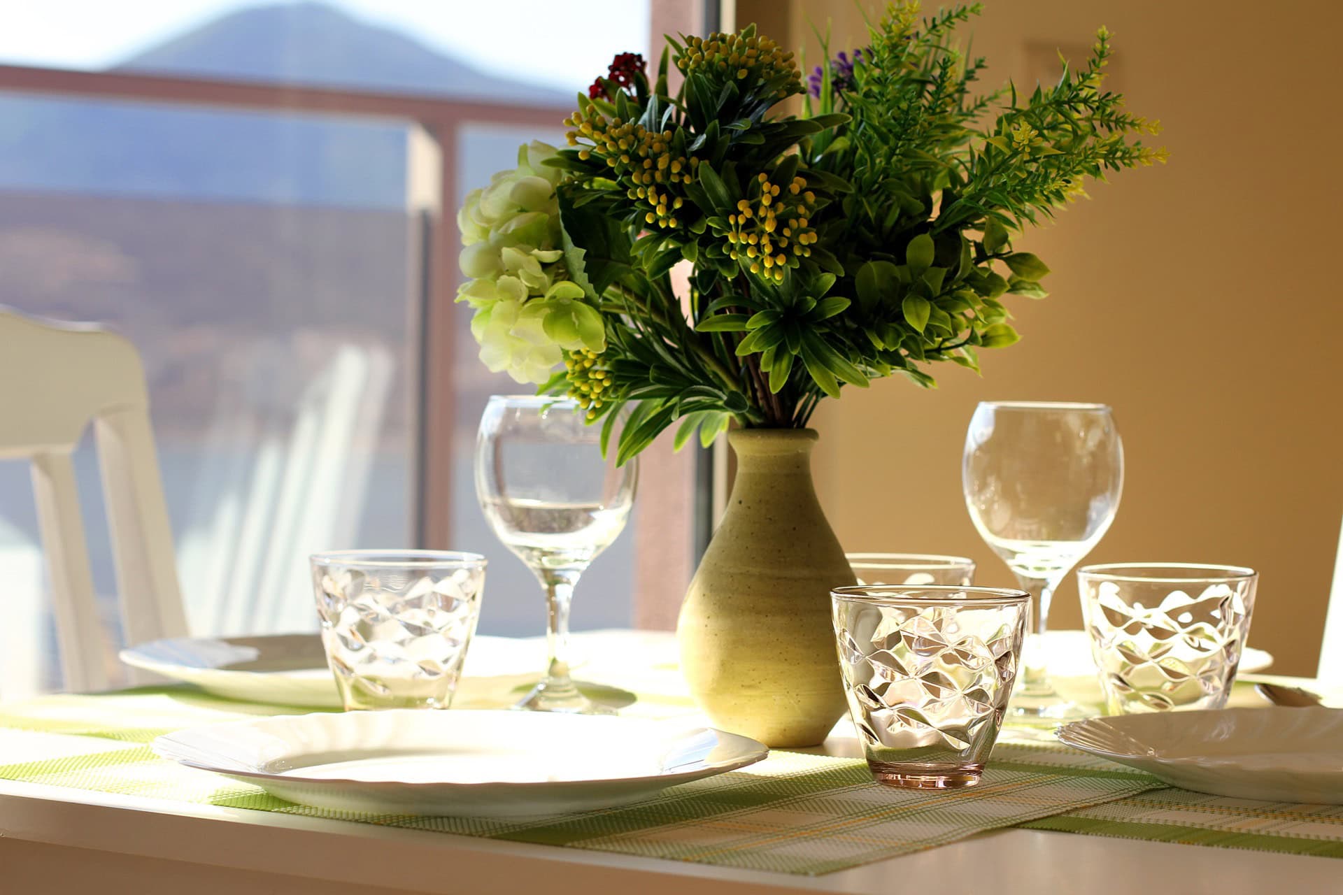 Table setting with flowers in the living room of an apartment in Bečići, Montenegro, with a mountain view from the panoramic window.