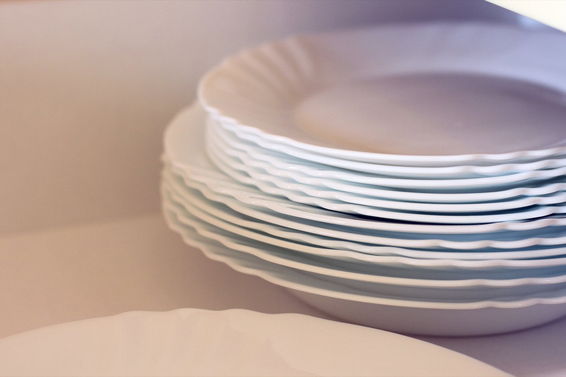 Stack of white plates with a wavy edge in the kitchen cabinet of an apartment in Bečići, Montenegro, property No. 1768.