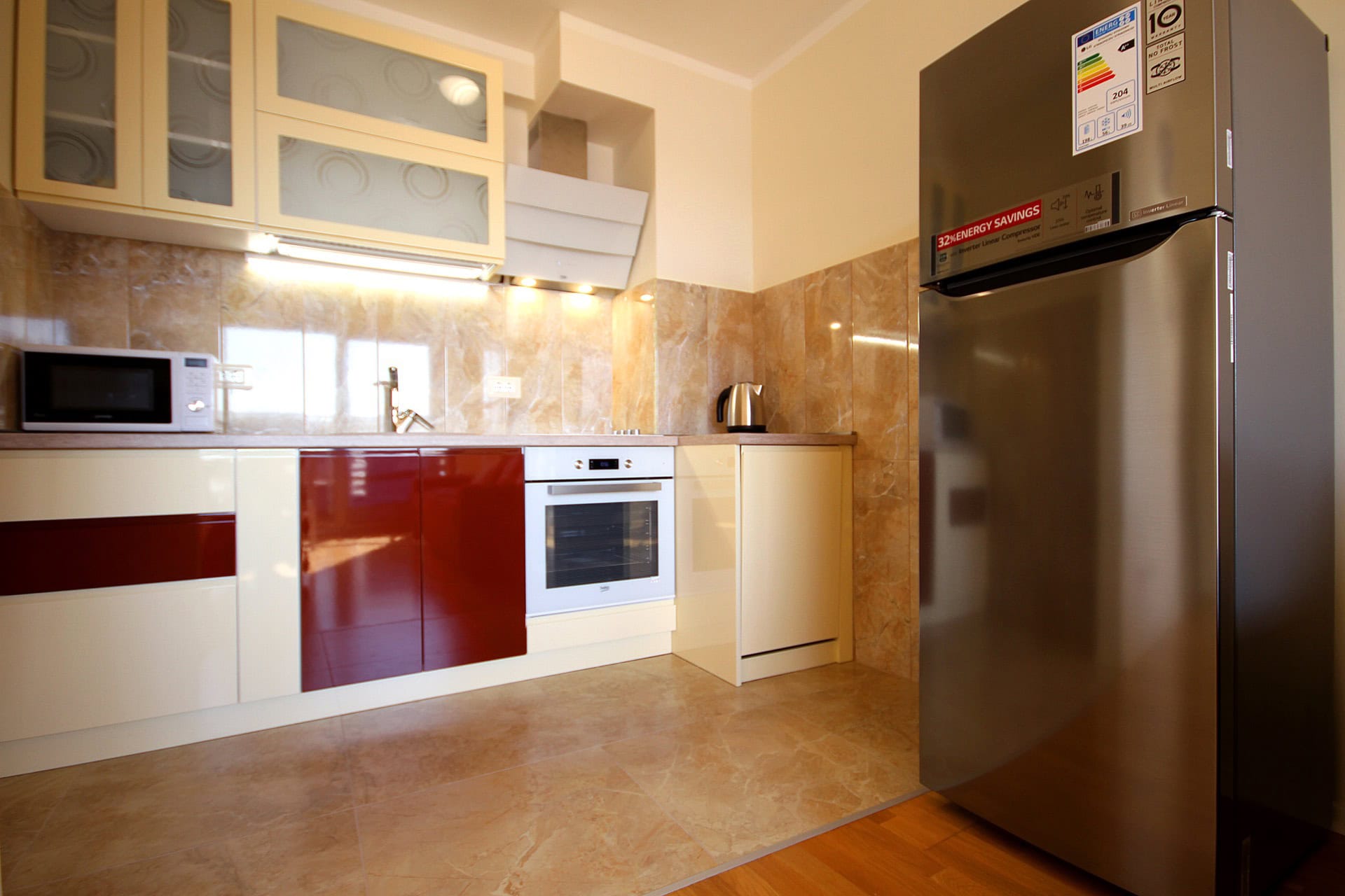 Modern kitchen in an apartment in Bečići, Montenegro: glossy cabinetry, built-in appliances, and marble-look tile finishes.