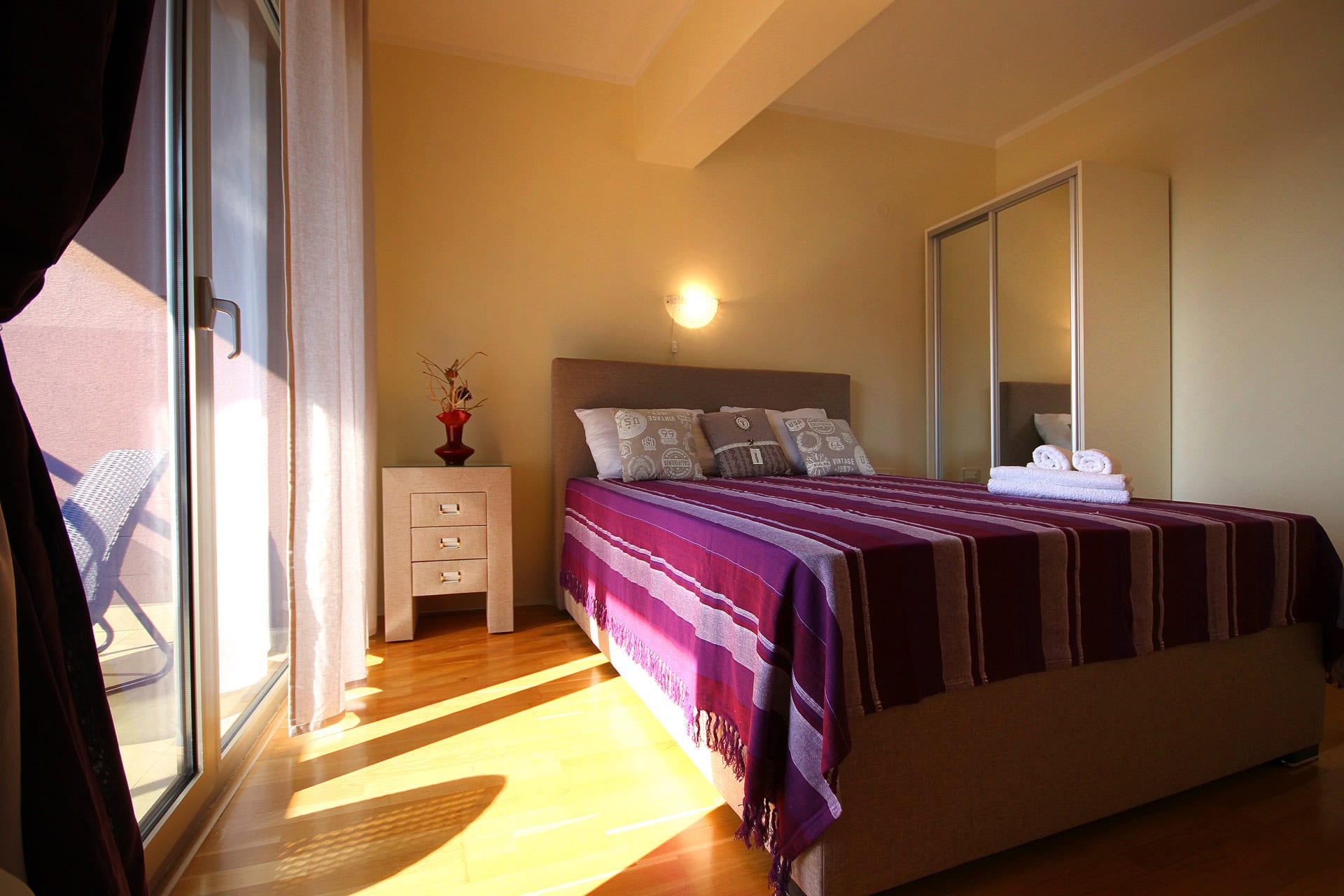 Cozy bedroom with a double bed, mirrored wardrobe, and access to the terrace in an apartment, Becici, Montenegro.