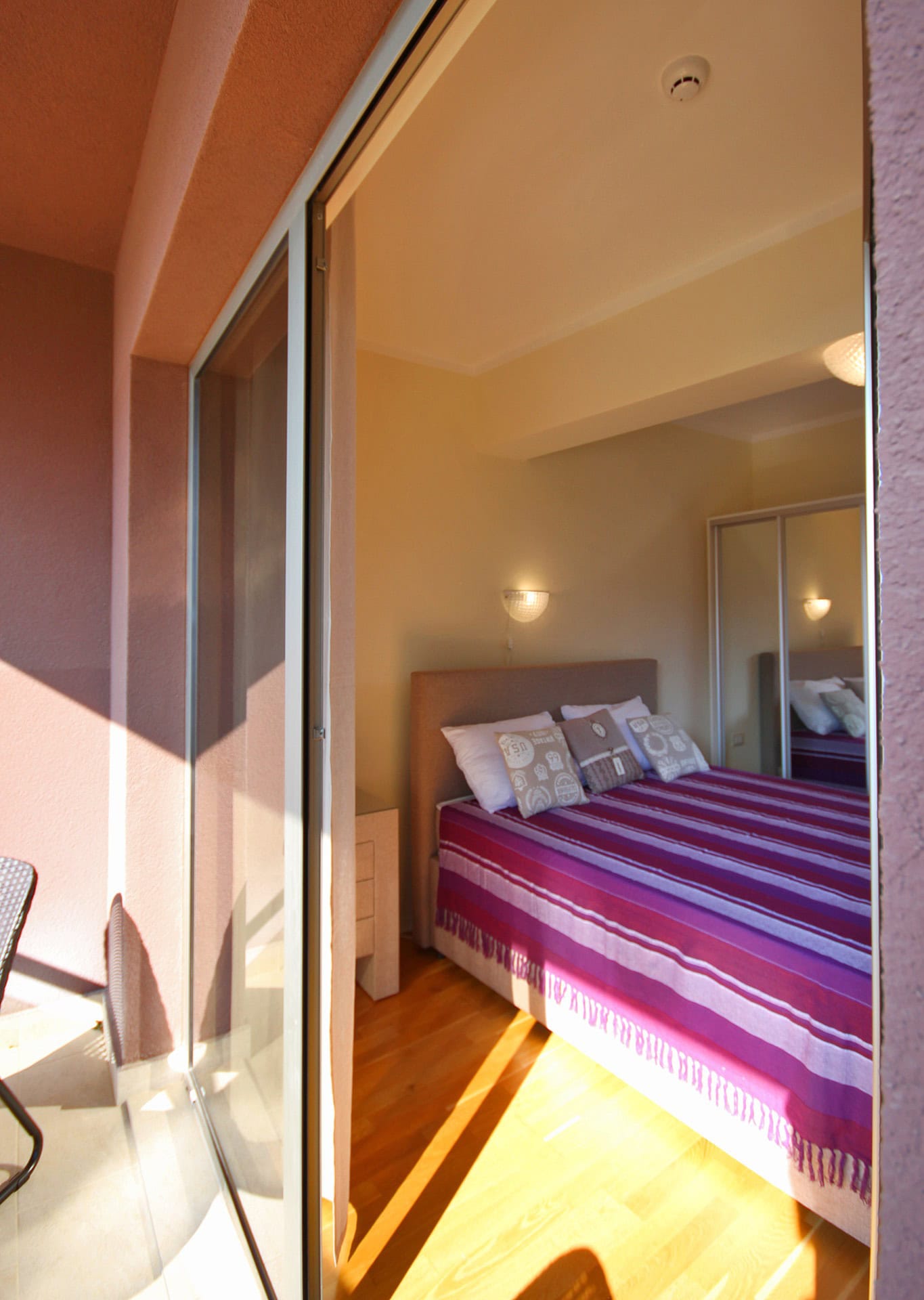 Bedroom with a double bed and access to the balcony in an apartment in Bečići, Montenegro. Parquet flooring, built-in wardrobe, cozy interior.