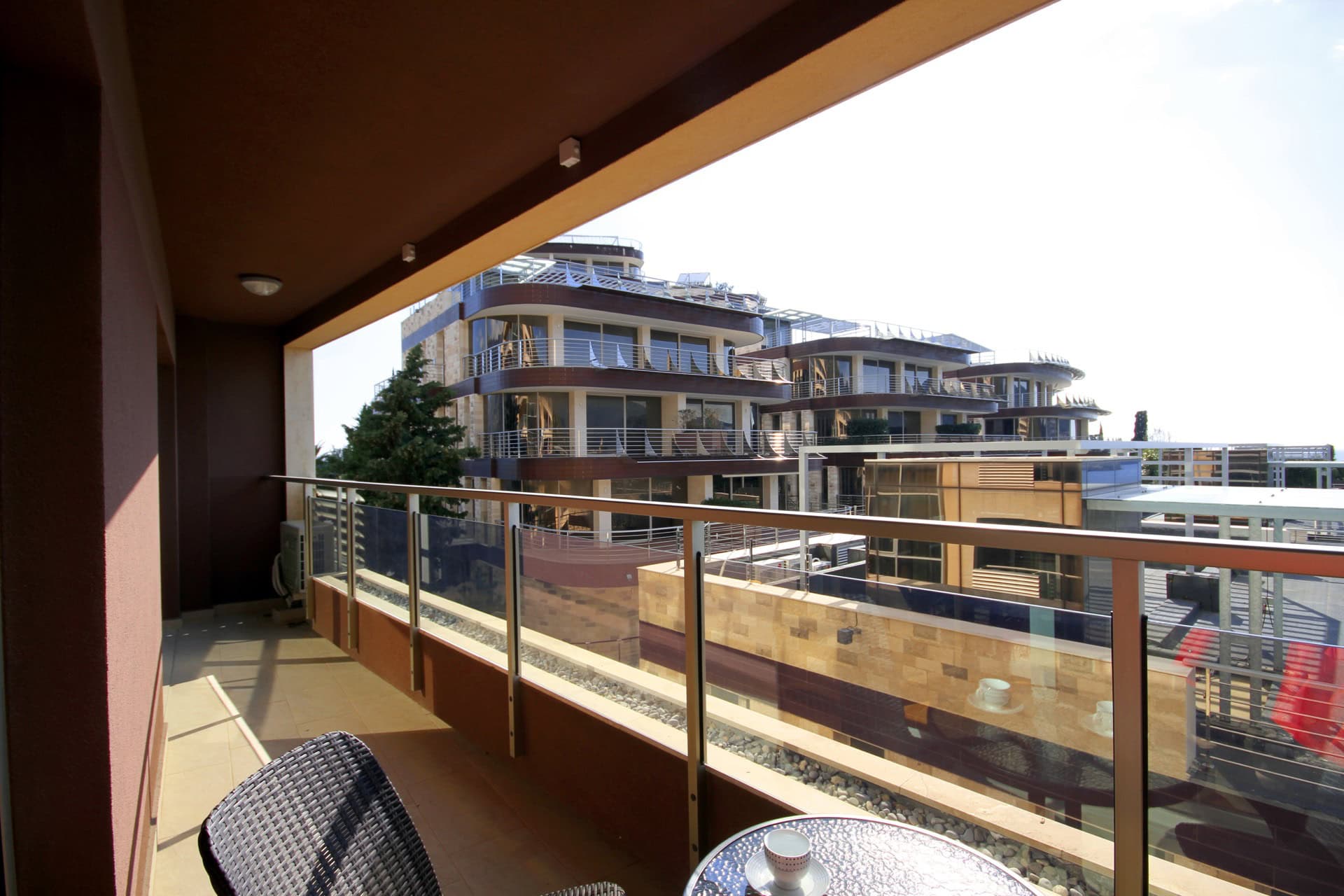 Spacious balcony with wicker furniture and a view of modern residential complexes in Bečići, Montenegro.