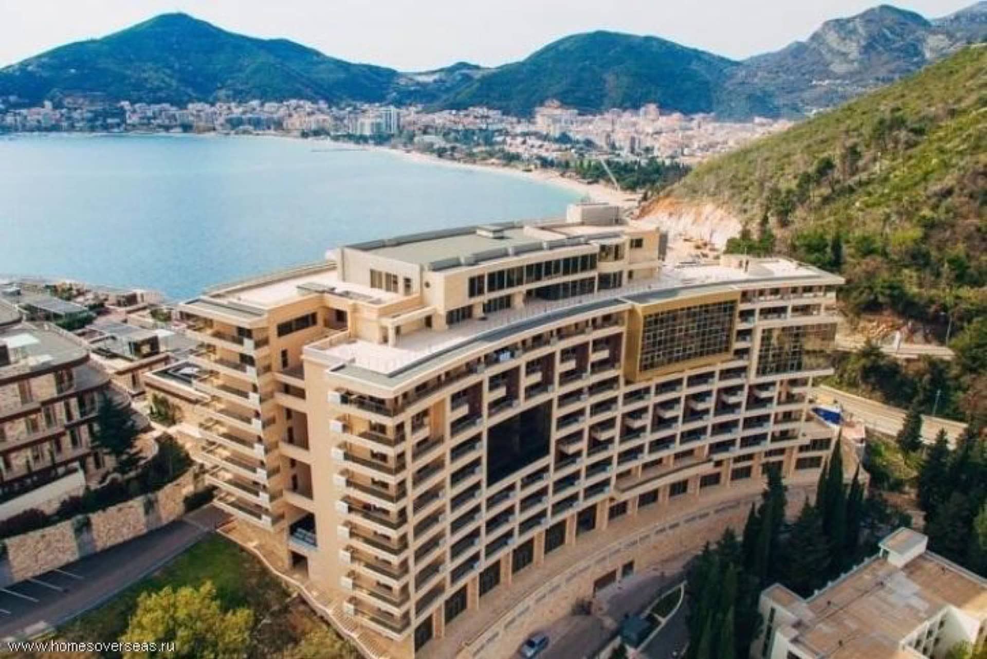 Modern residential complex by the sea in Bečići, Montenegro: aerial view of the building with terraces and the coastal panorama.