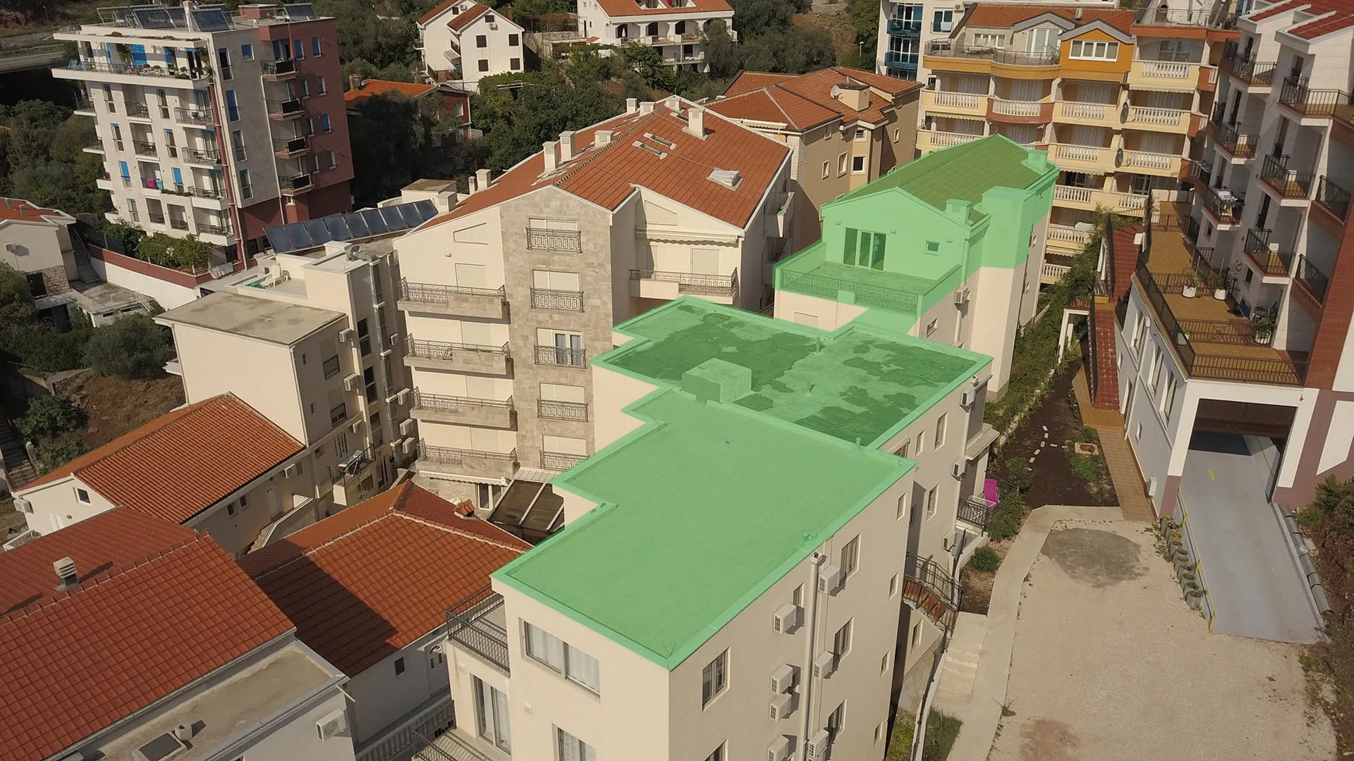 Aerial view of residential buildings featuring green and red roofs, balconies, and solar panels.