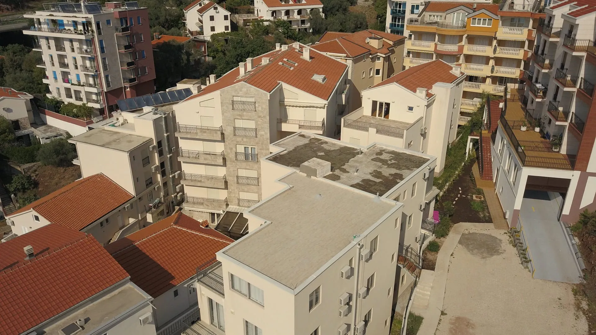 Aerial view of residential buildings with red tiled roofs and balconies.