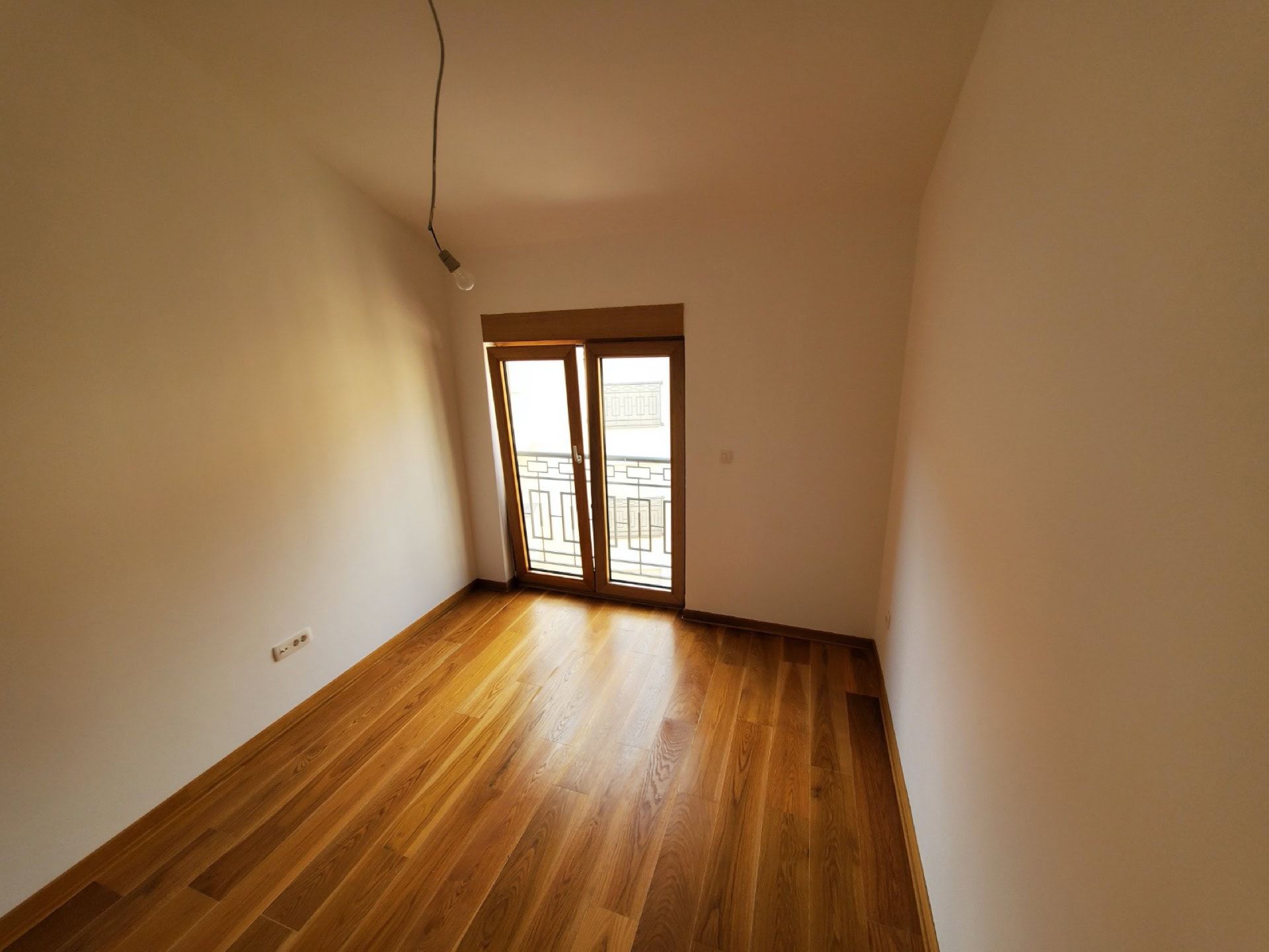 Bright bedroom with wooden flooring and access to the balcony in a penthouse, Pržno, Montenegro.