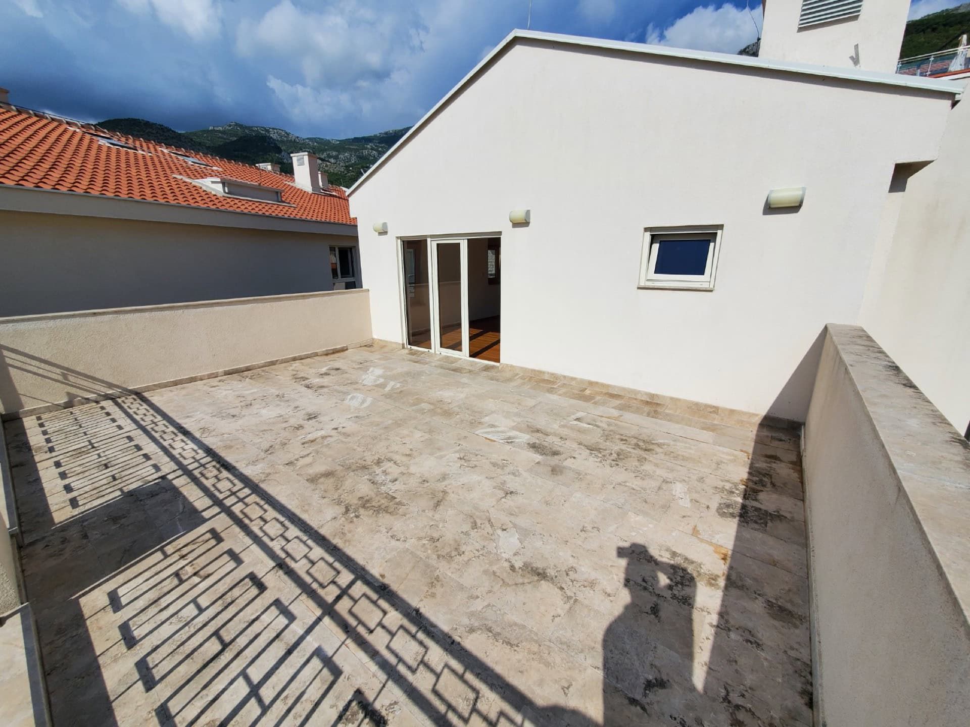 Spacious open penthouse terrace in Pržno, Montenegro, with stone flooring and mountain views.