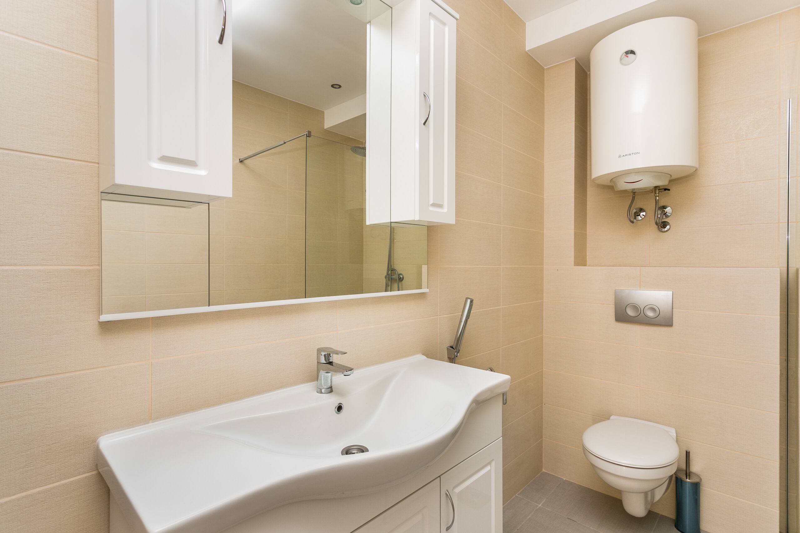 Modern bathroom in a penthouse, Rafailovići, Montenegro: white fixtures, shower cabin, and Ariston water heater.