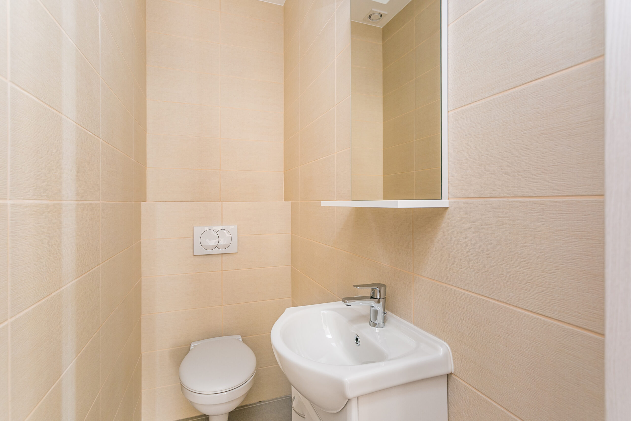 Modern bathroom in a penthouse, Rafailovići, Montenegro: beige tiles, wall-mounted toilet and sink.
