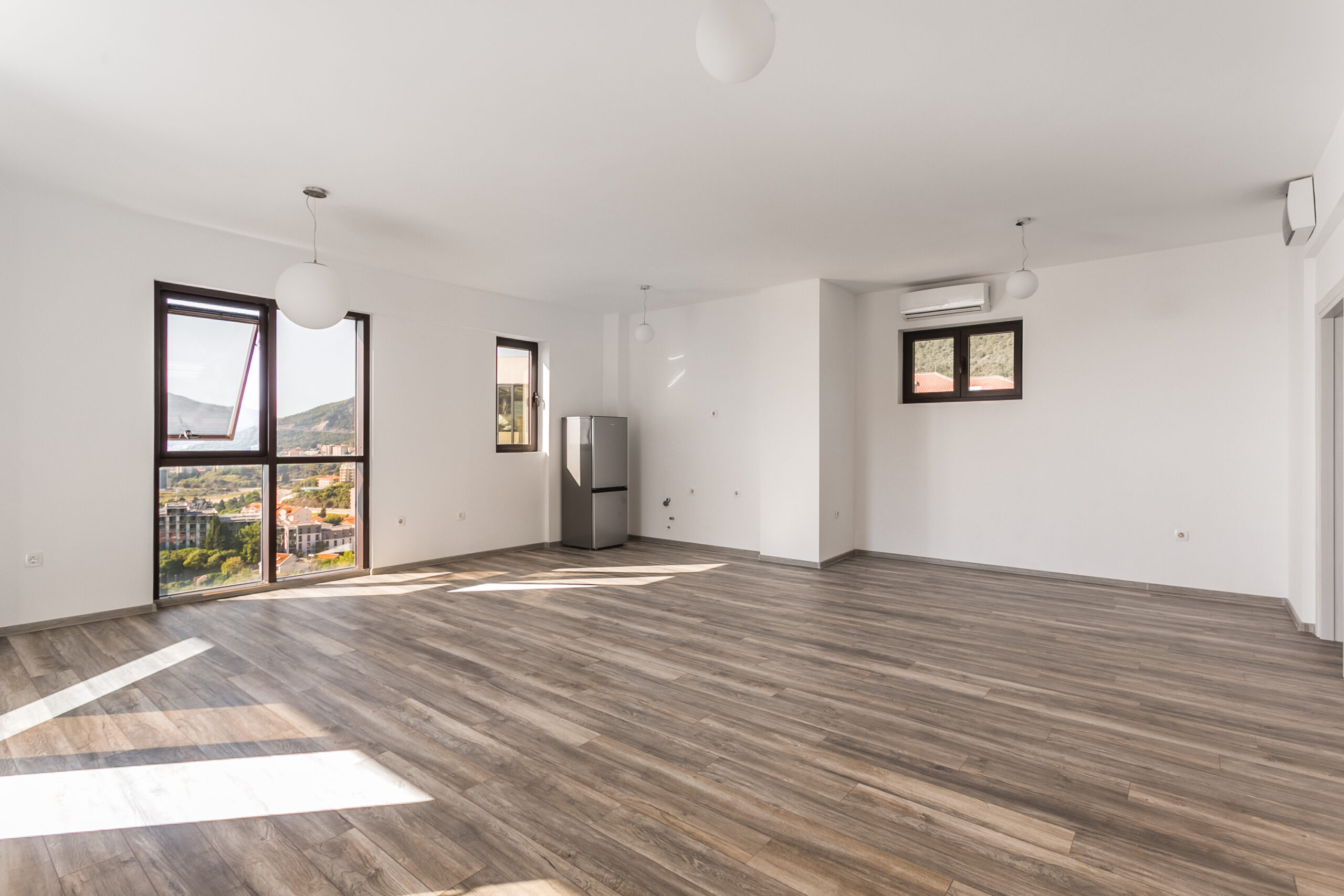 Bright living room in a penthouse, Rafailovići, Montenegro: panoramic windows with sea view, laminate flooring, and air conditioning.