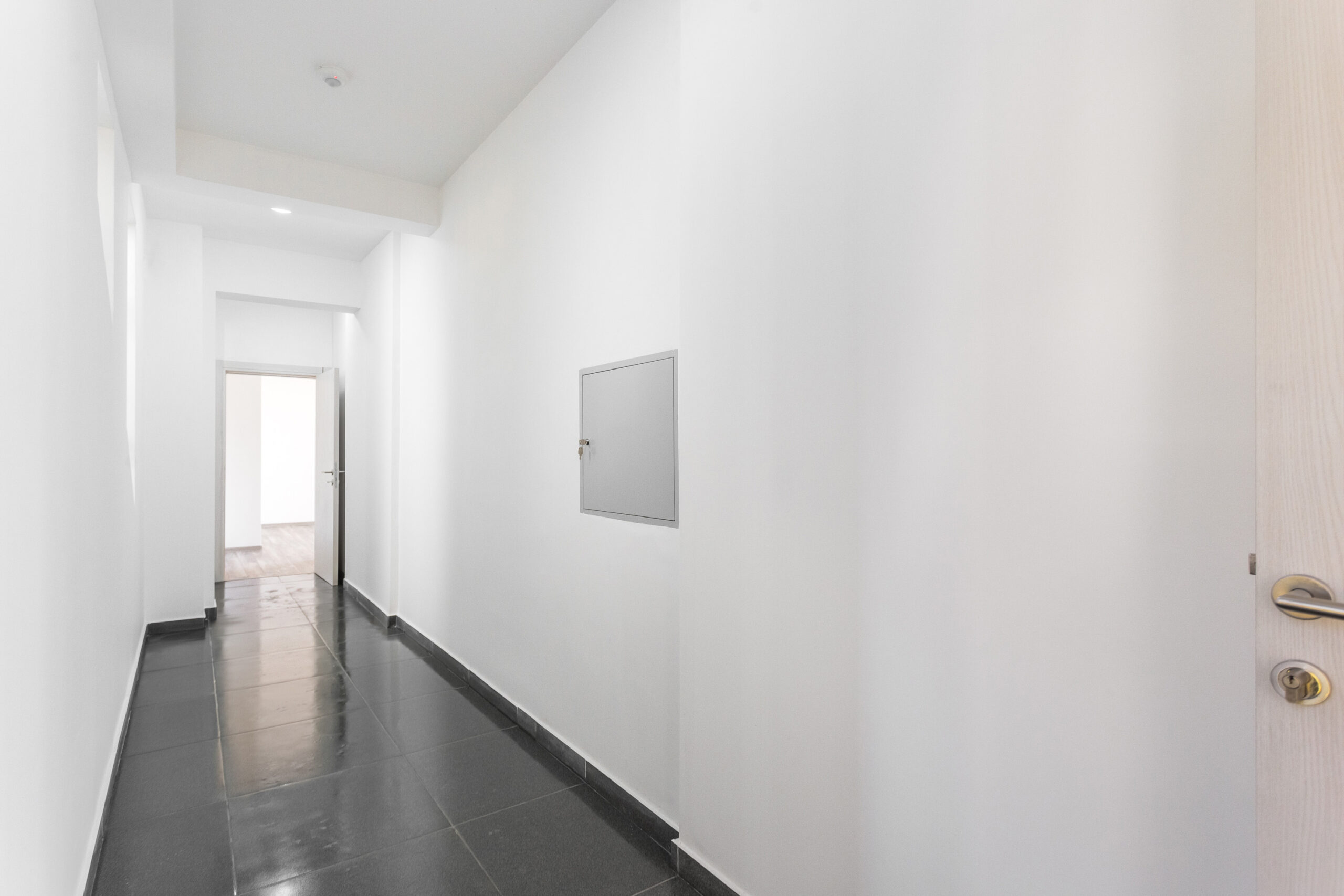 Bright hallway in an apartment in Rafailovici, Montenegro: white walls, gray tiled floor, and interior doors.