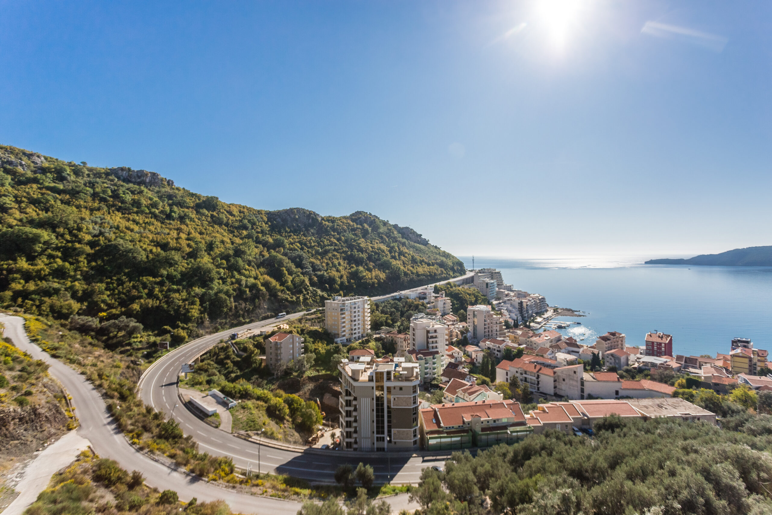Panoramic view of the Rafailovići coast, Budva Riviera, Montenegro: residential buildings, mountain landscape, and the sea.