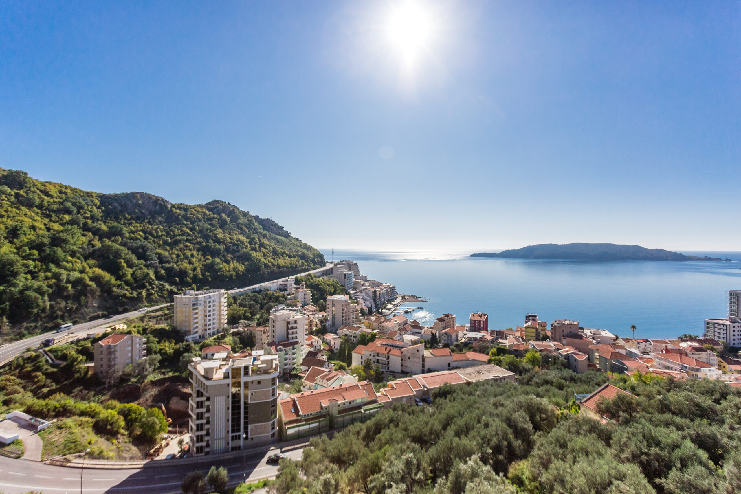 Panoramic view of the sea and the resort of Rafailovići, Budva Riviera, Montenegro: urban buildings and green hills.