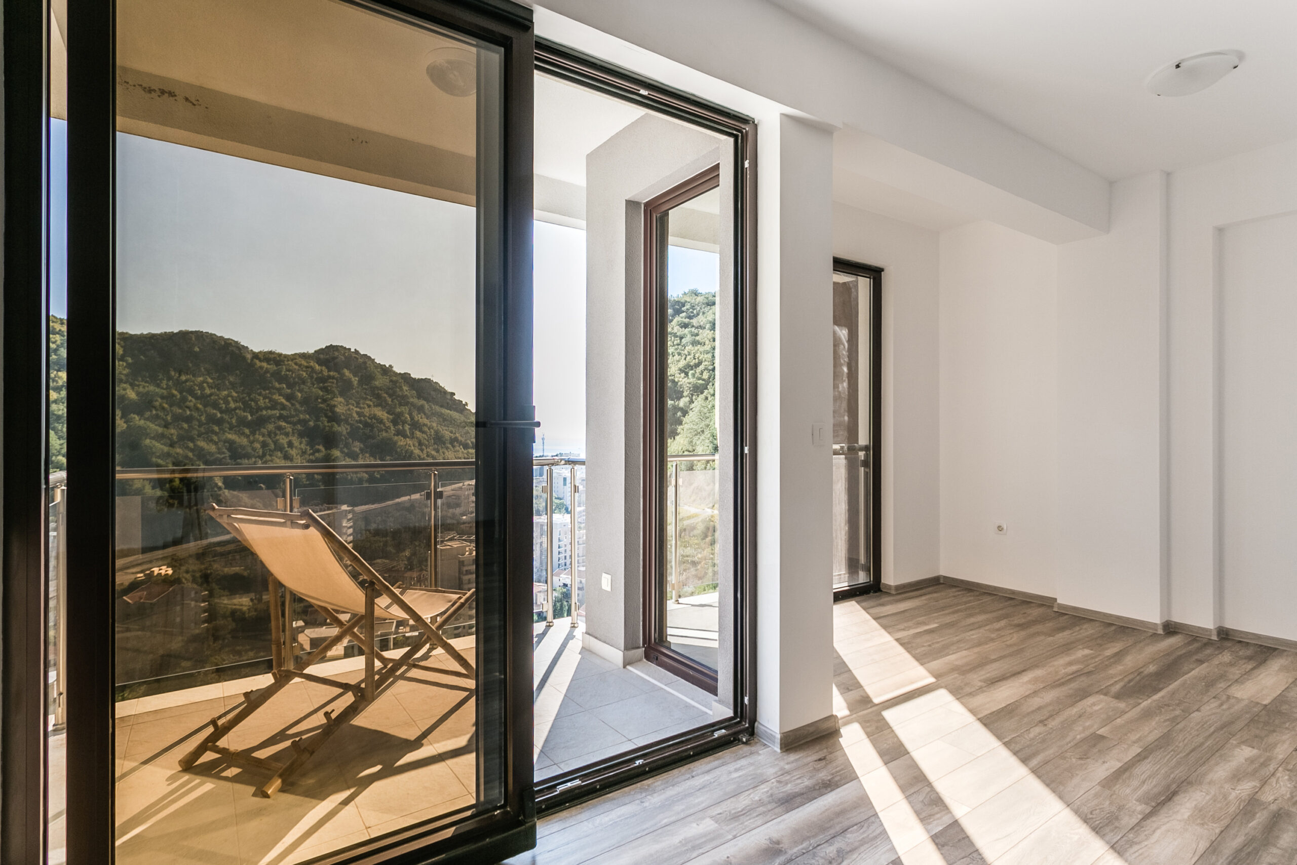 Bright living room in a penthouse in Rafailovići, Montenegro, with access to the balcony and panoramic mountain and sea views.