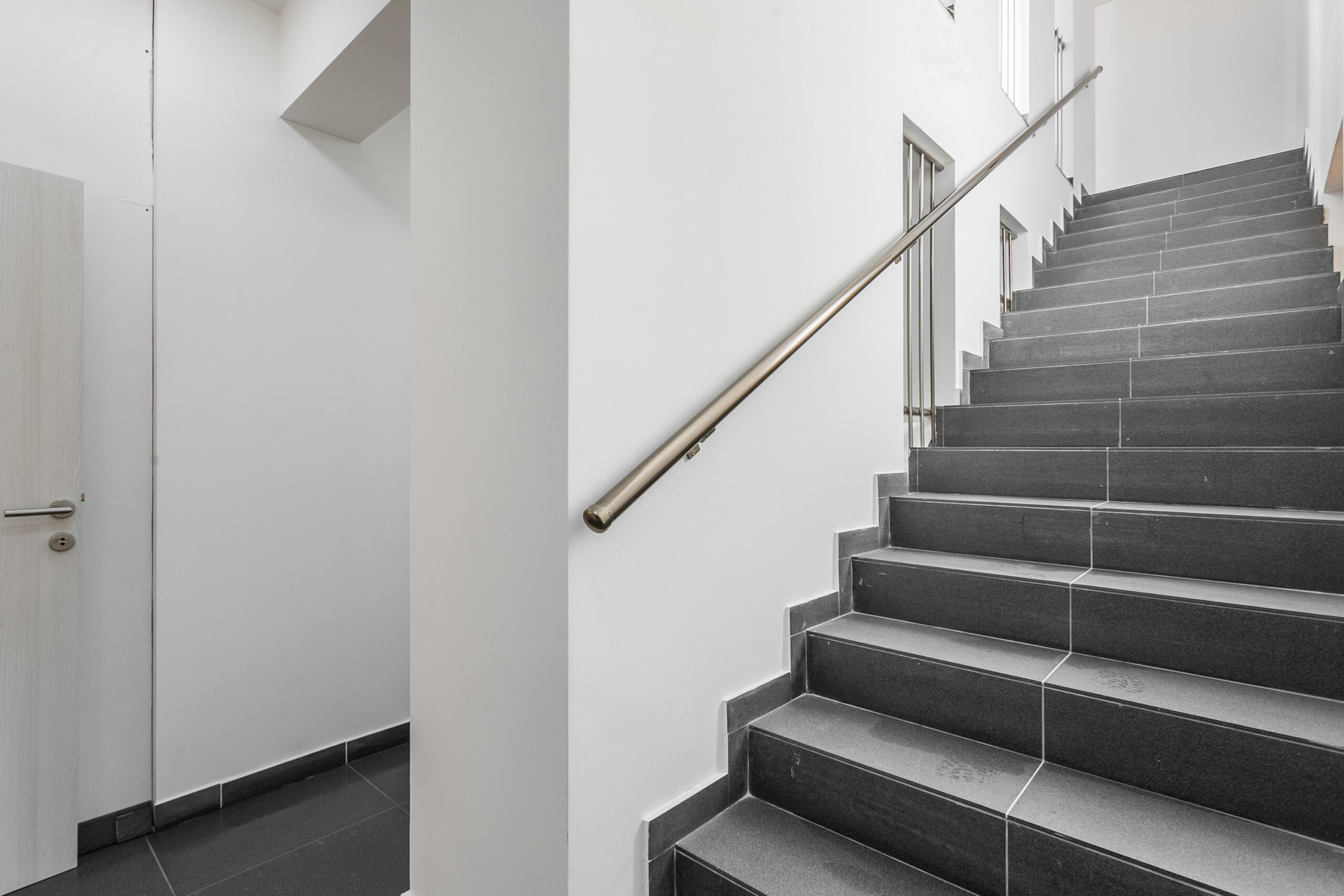 Modern staircase with dark porcelain stoneware finish and metal railings in a penthouse, Rafailovici, Montenegro