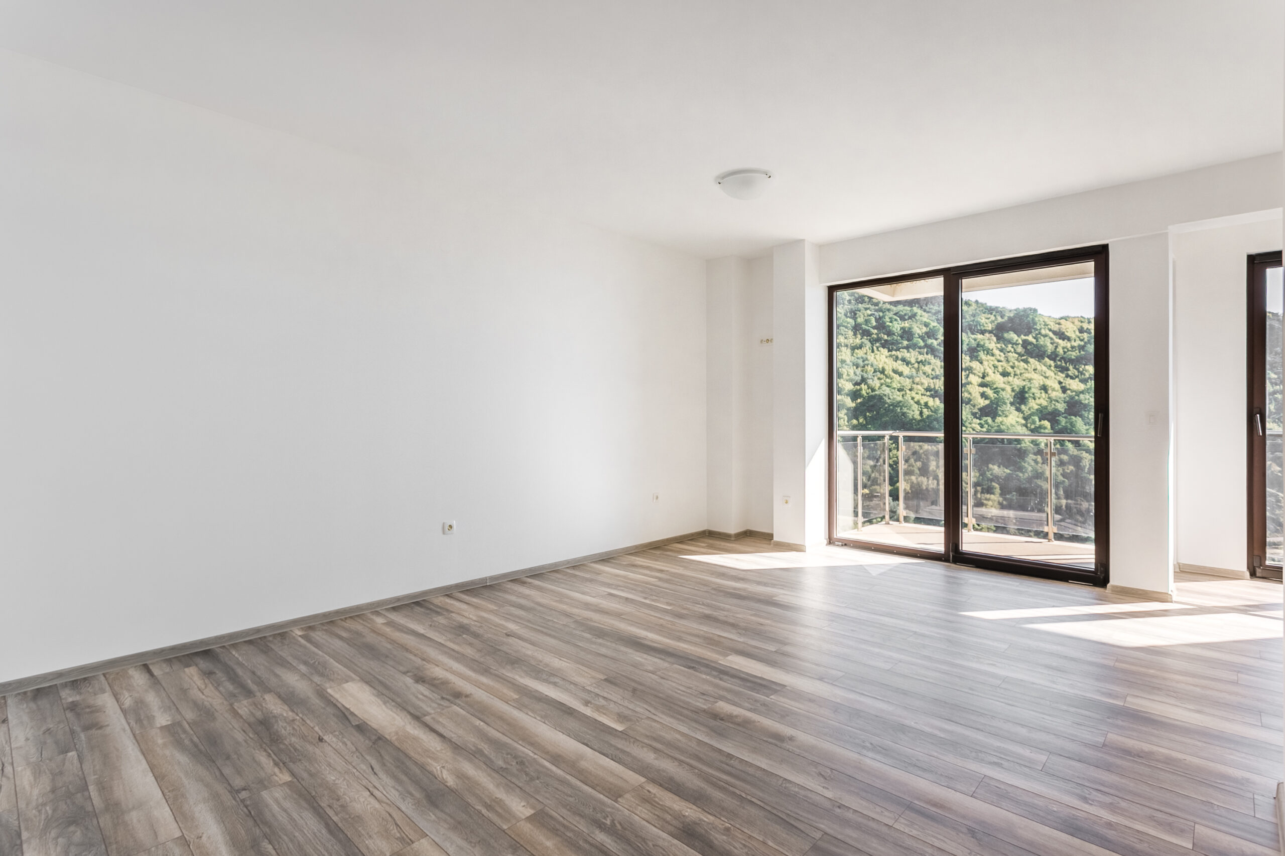 Bright empty living room with a panoramic window and mountain view in a penthouse, Rafailovici, Budva Riviera, Montenegro.