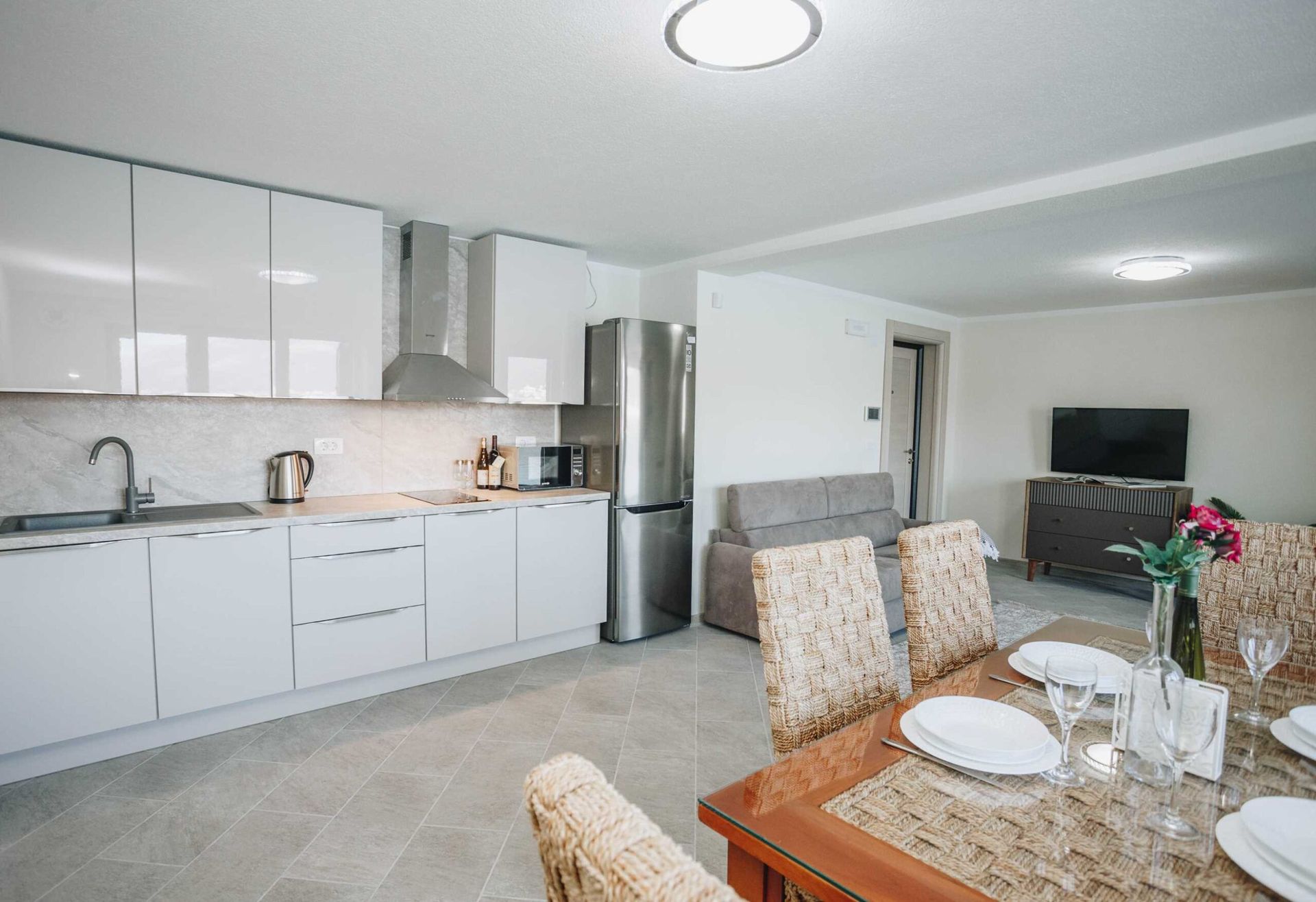 Modern kitchen-living room in a villa in Krašići, Montenegro: white furniture, dining area, and appliances.