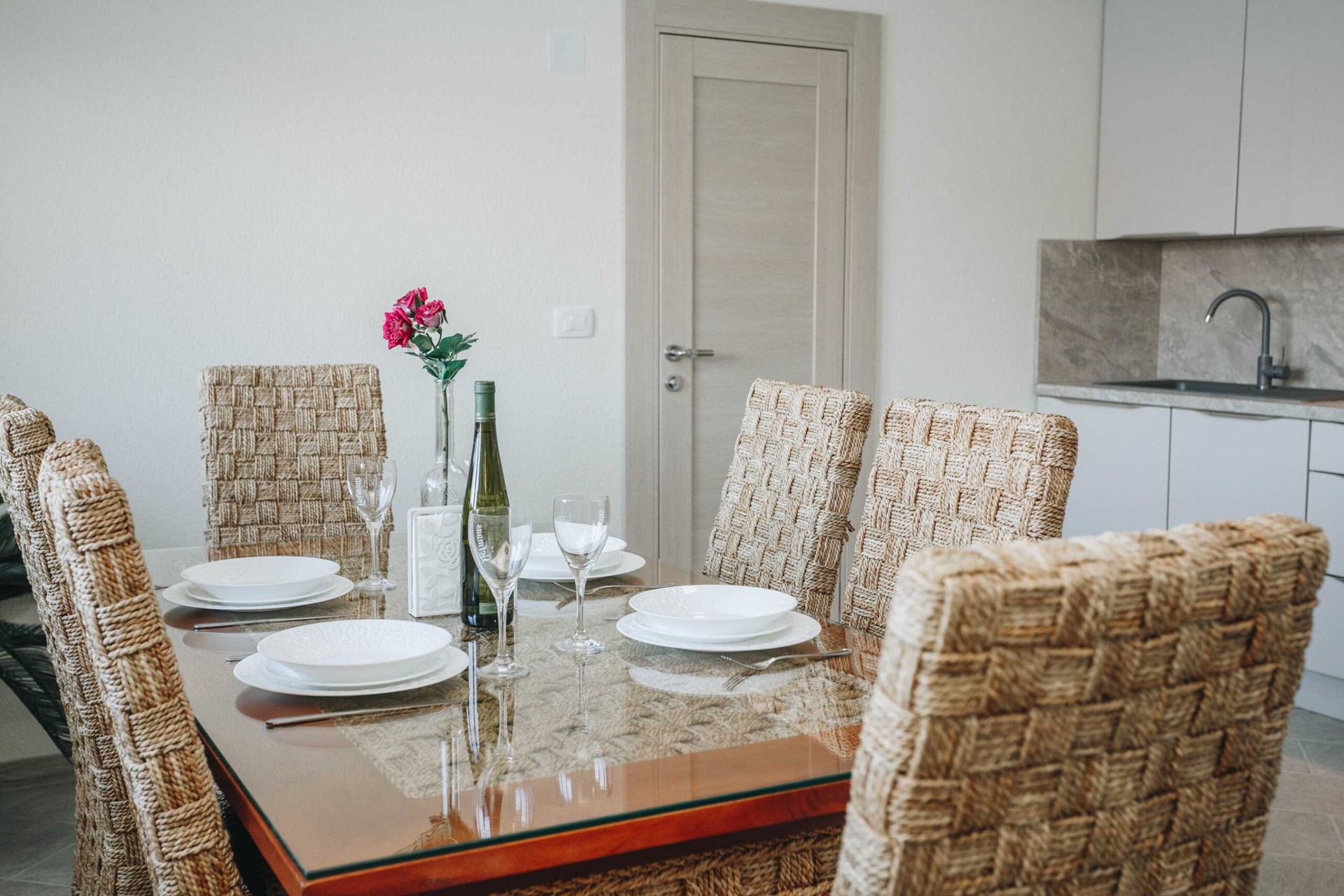 Dining area with wicker chairs and a glass table in a villa in Krašići, Montenegro. Modern kitchen interior.