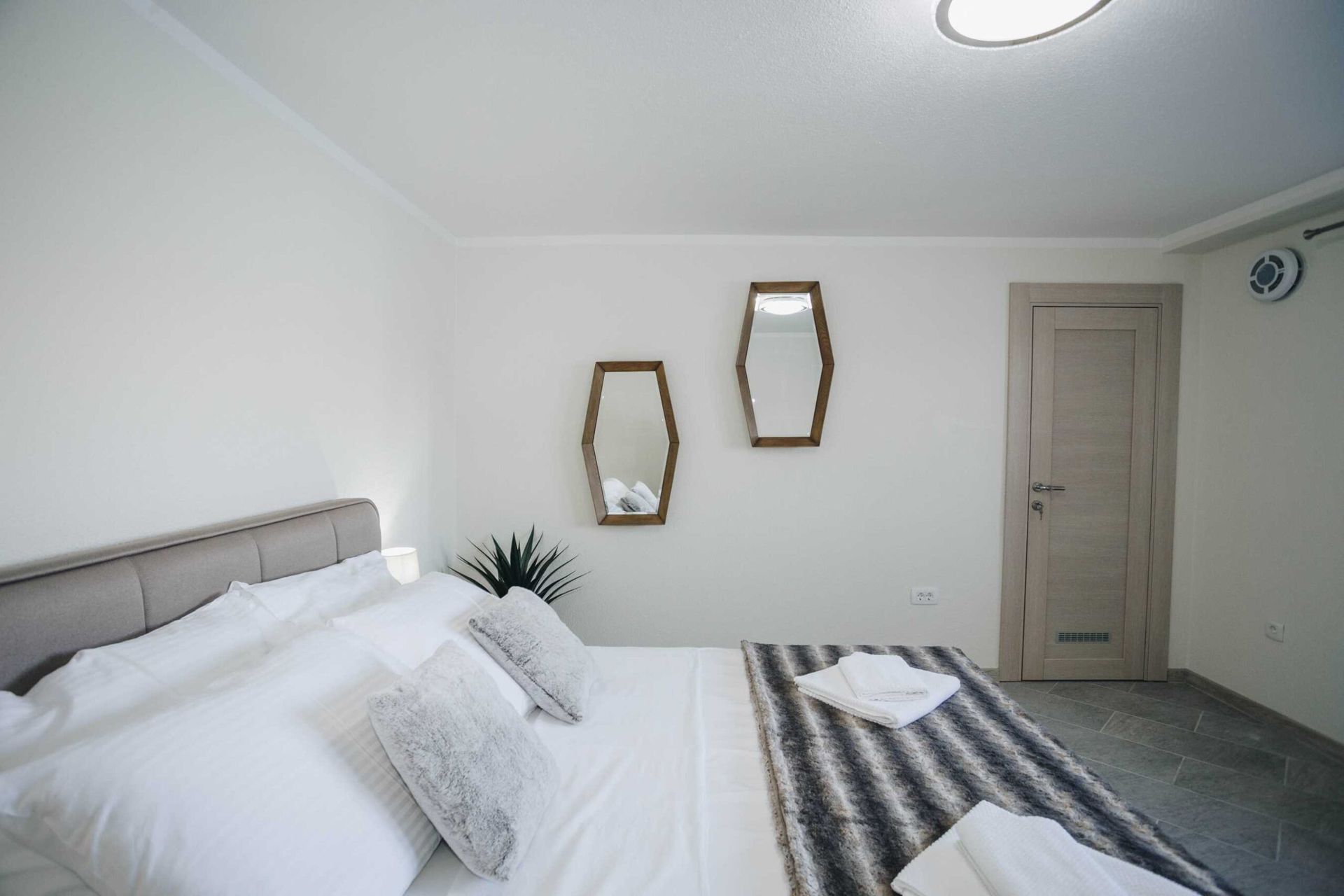 Modern bedroom with a double bed and mirrors in a villa, Krašići, Montenegro: stylish interior and cozy atmosphere.