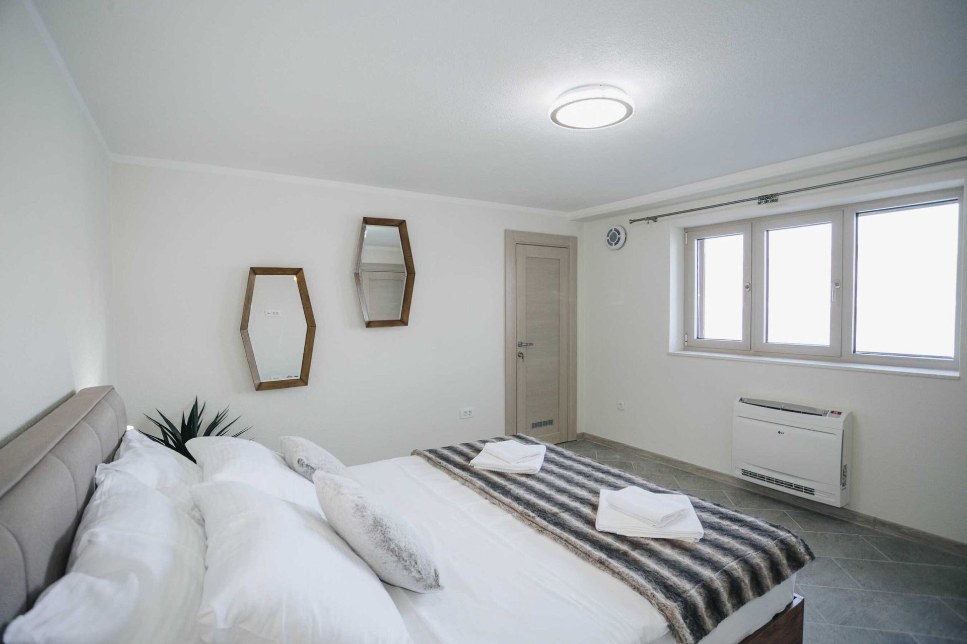 Bright bedroom with a double bed and mirrors in the Krashichi villa, Montenegro: modern interior and air conditioning.